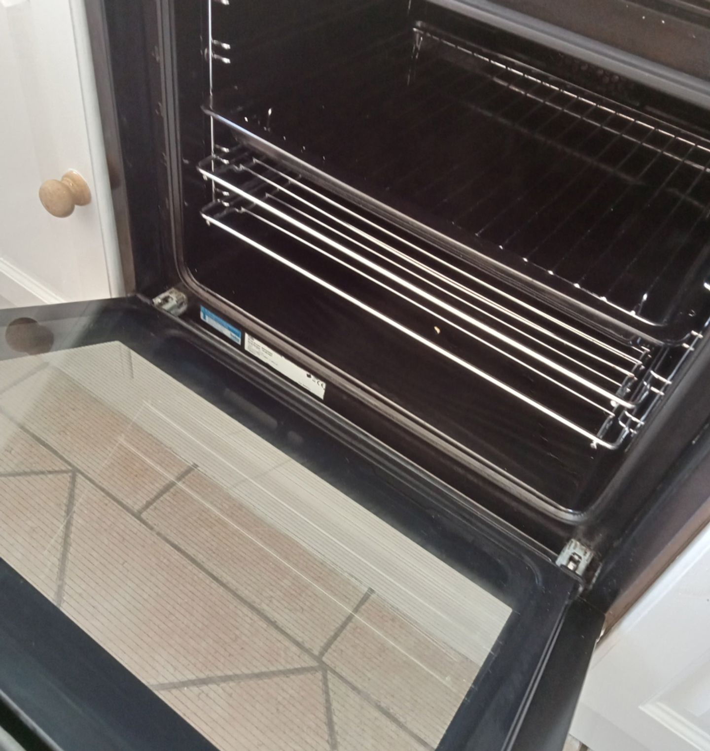 Gloved hand wiping down a soapy oven door