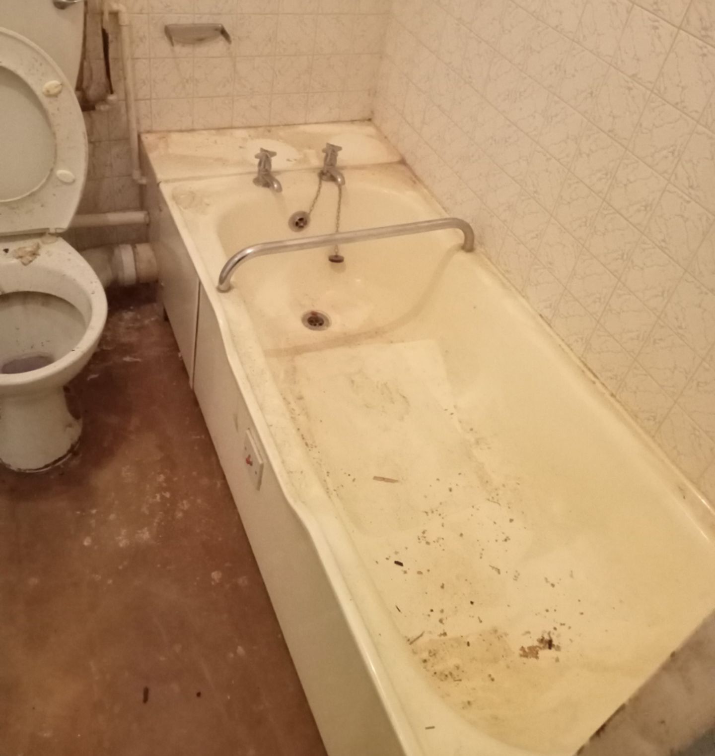 Grimy, stained bathtub and toilet in a neglected bathroom before cleaning