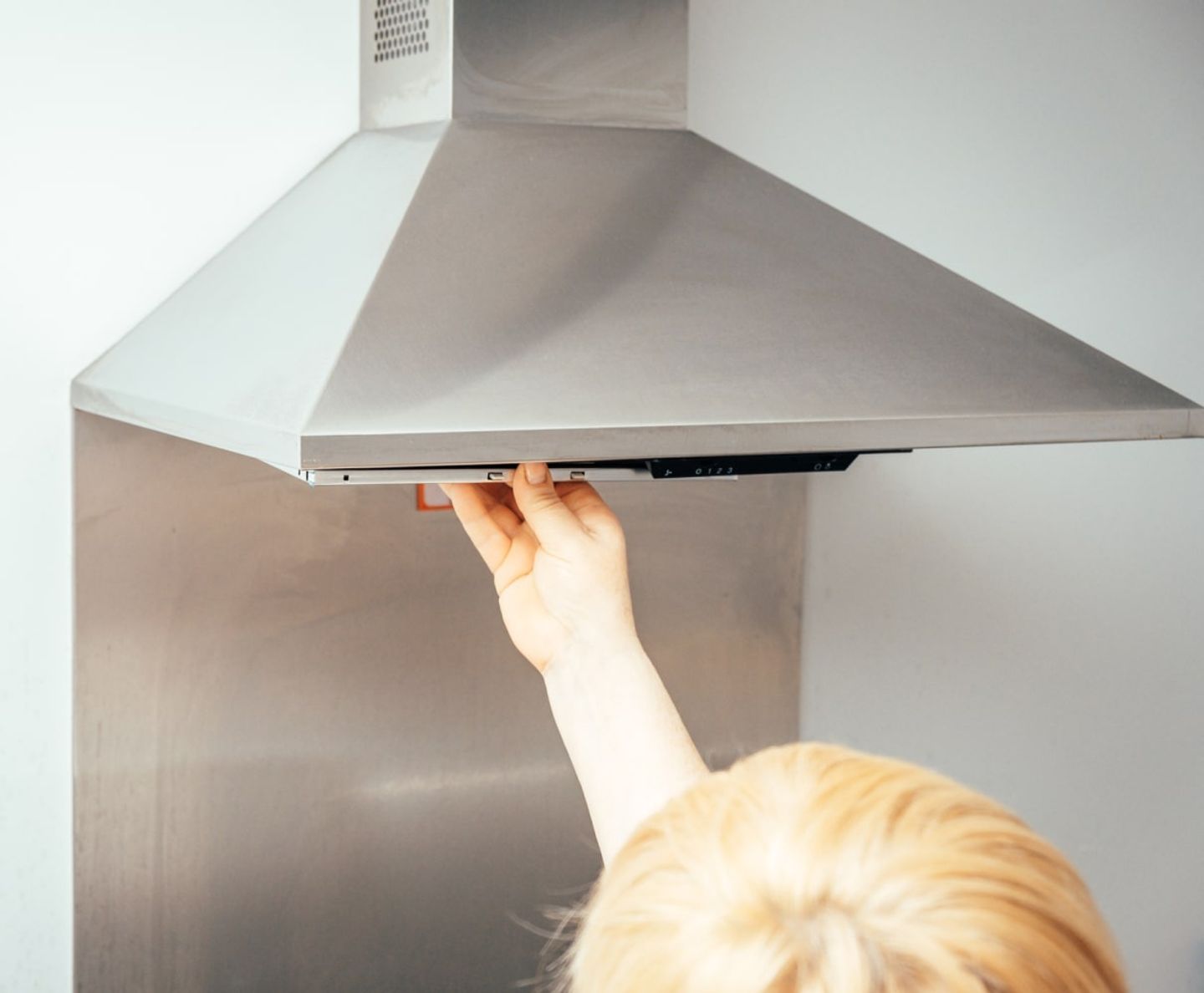 Person cleaning a stainless steel cooker extractor hood