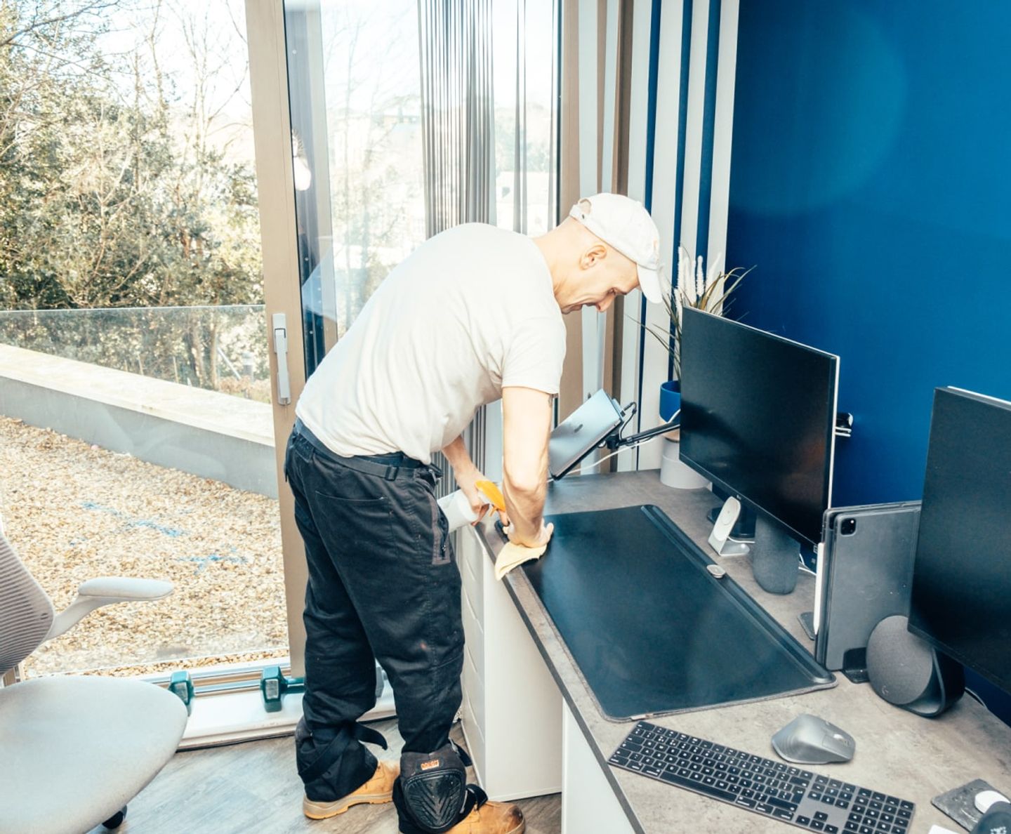 Eagle Family cleaner wiping a desk in a home office by a window