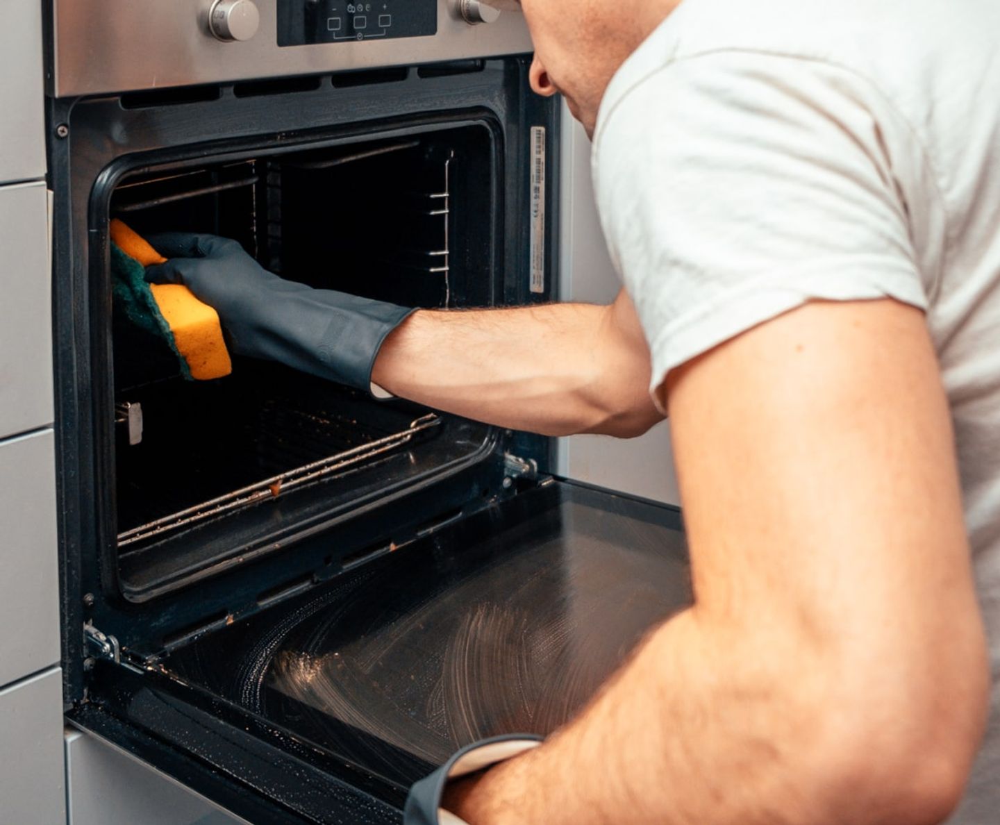 Cleaner scrubbing the interior of an oven with a sponge
