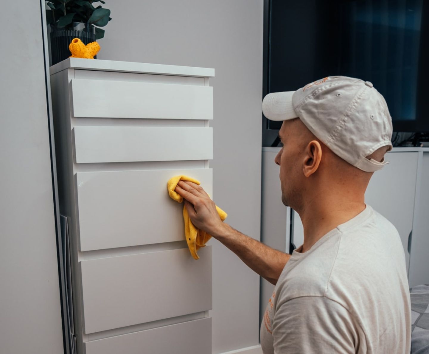 Eagle Family cleaner wiping down a white chest of drawers