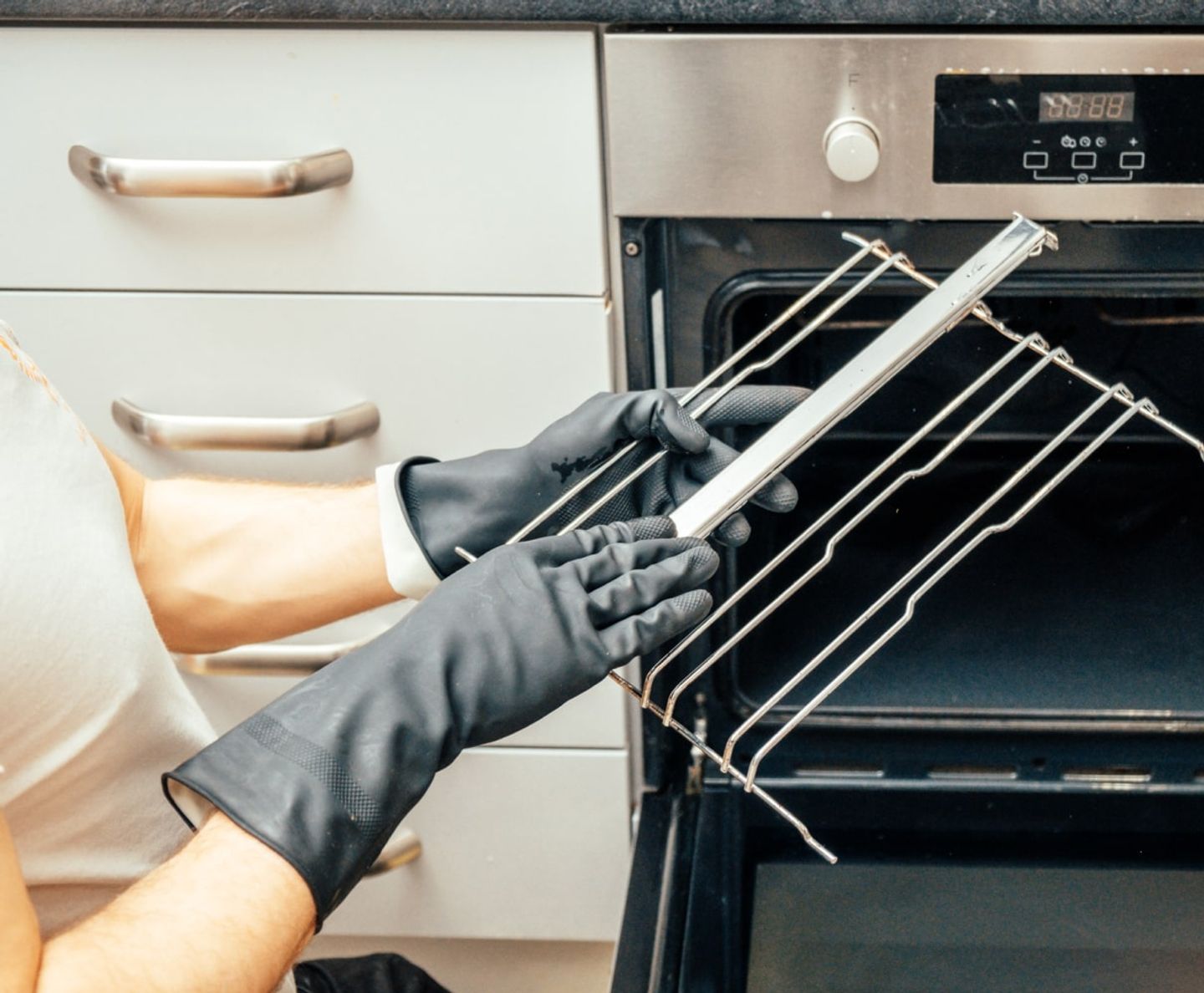 Gloved cleaner removing the wire shelf racks from an oven