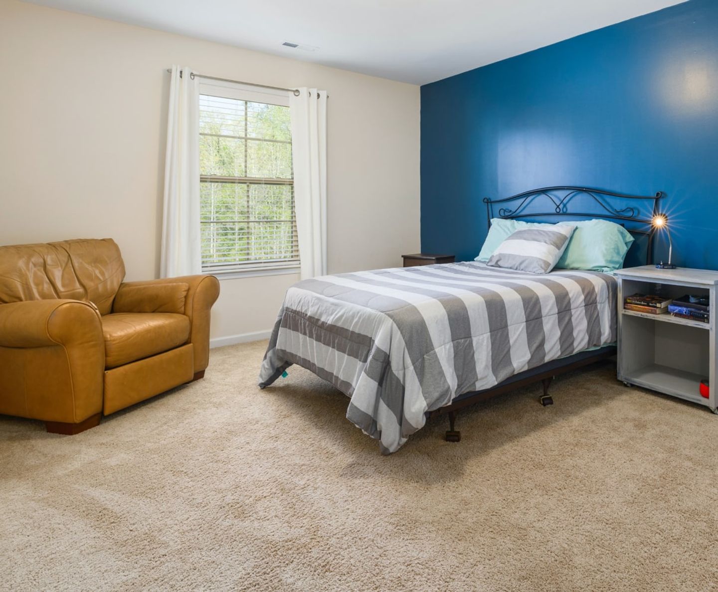 Tidy bedroom with clean beige carpet and a blue feature wall