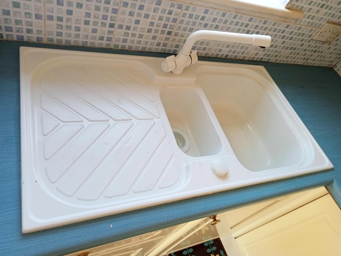 Clean white kitchen sink and drainer with a mosaic tiled splashback