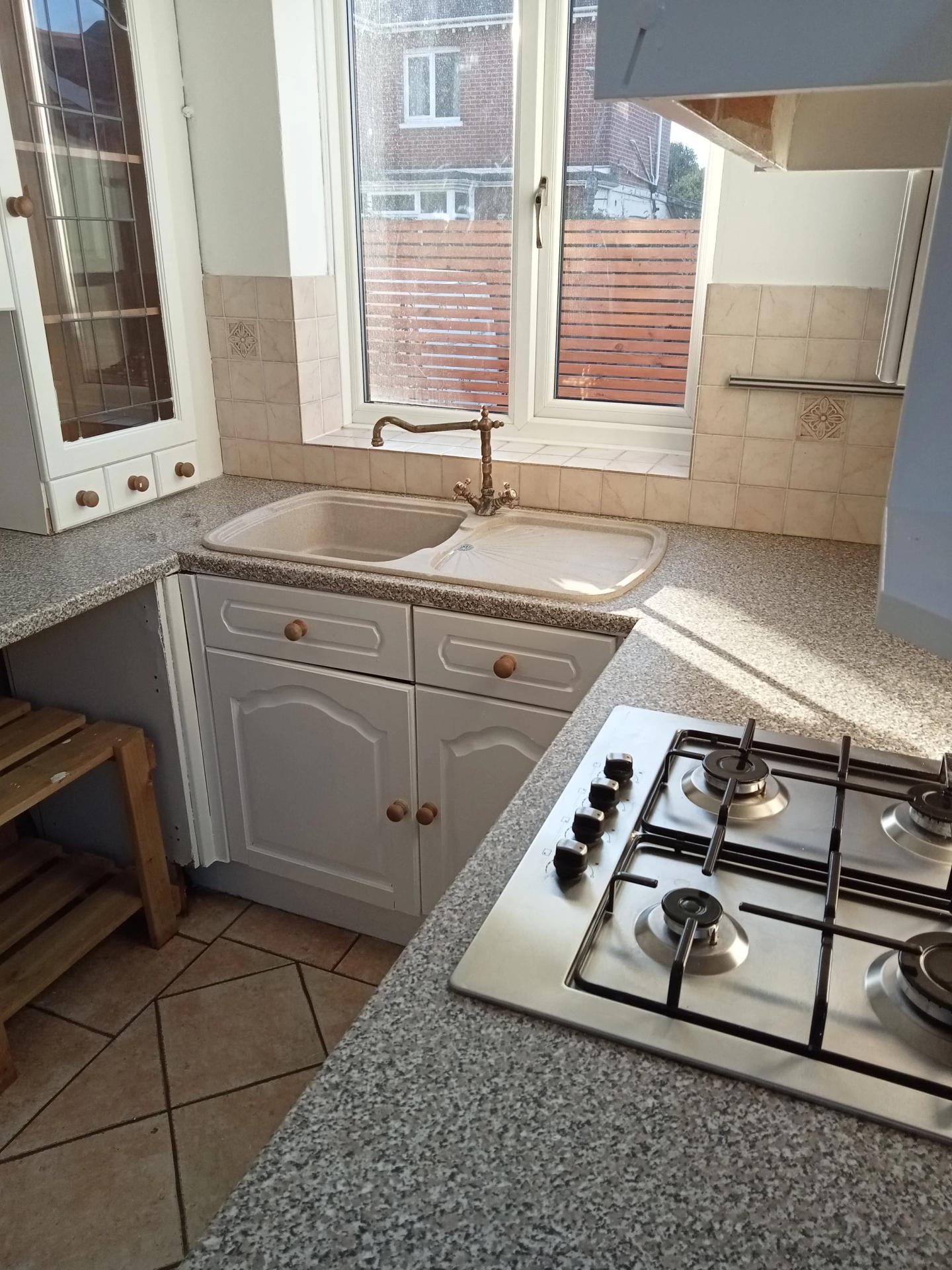 Cleaned kitchen with gas hob, sink and worktops in bright sunlight