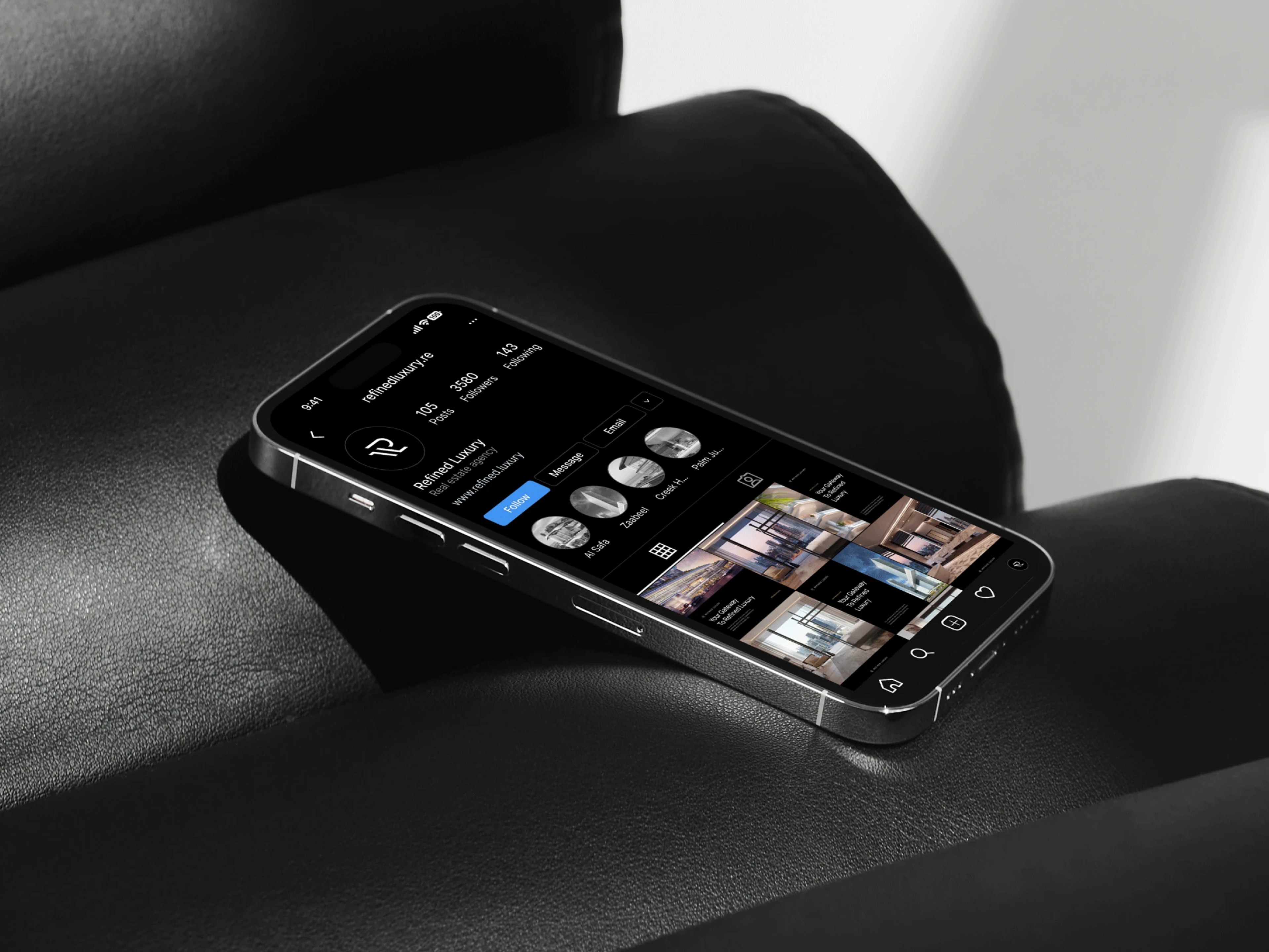 Phone showing the Refined Luxury Instagram profile on a black leather chair