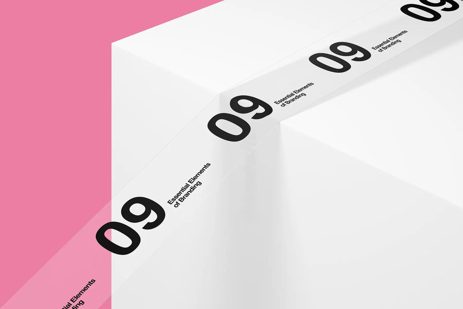 Ribbon printed with '09 Essential Elements of Branding' wrapping a white block on pink