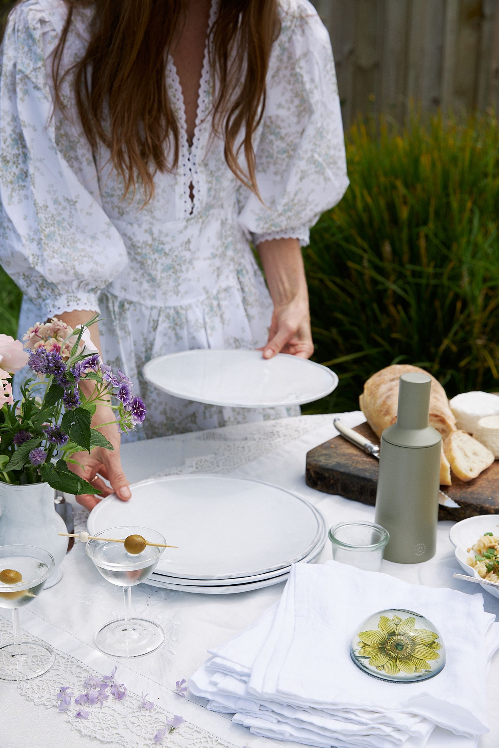 woman serves plates onto table wearing a floral dress