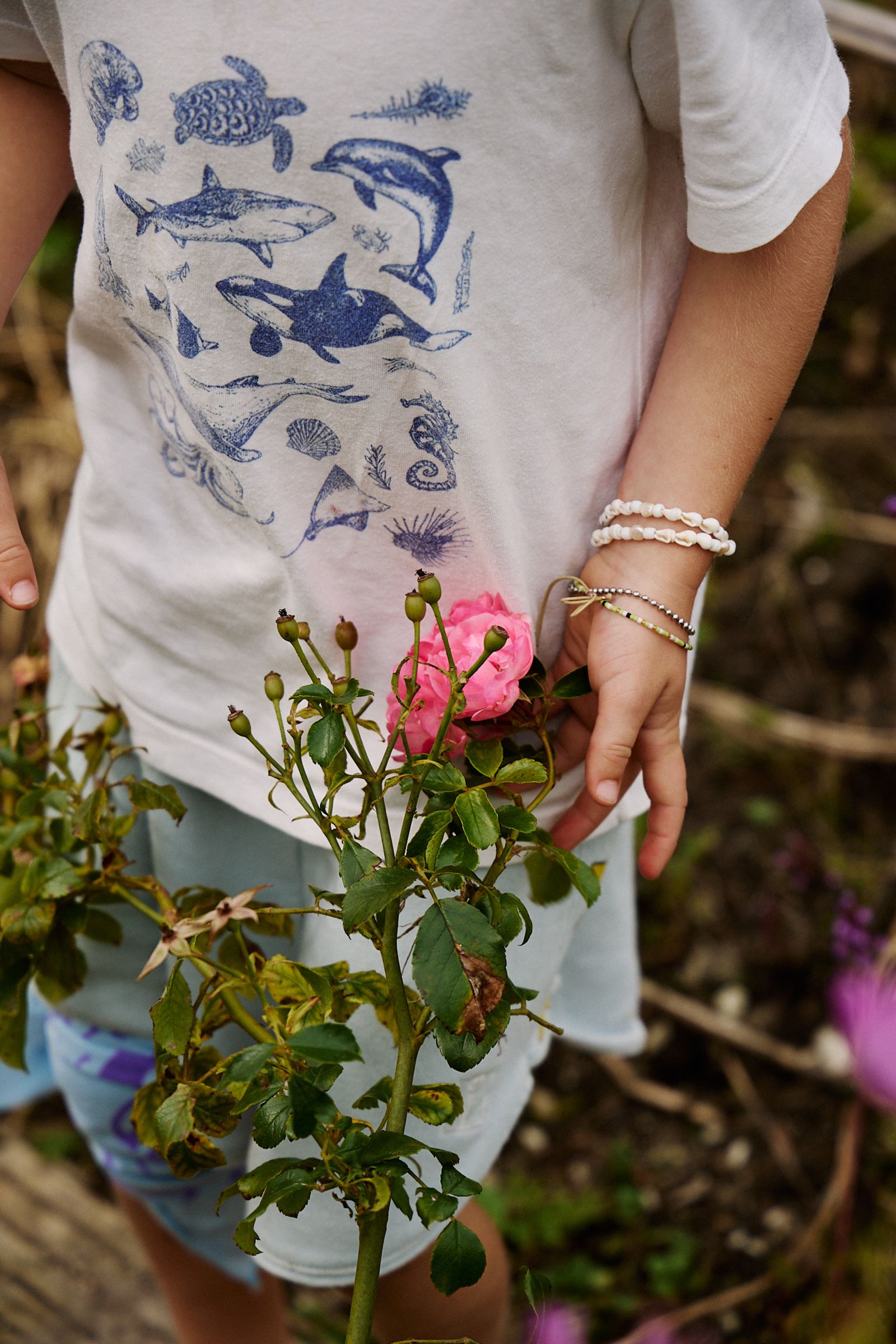 close up of small boy wearing a sea life t shirt and pearl bracelet