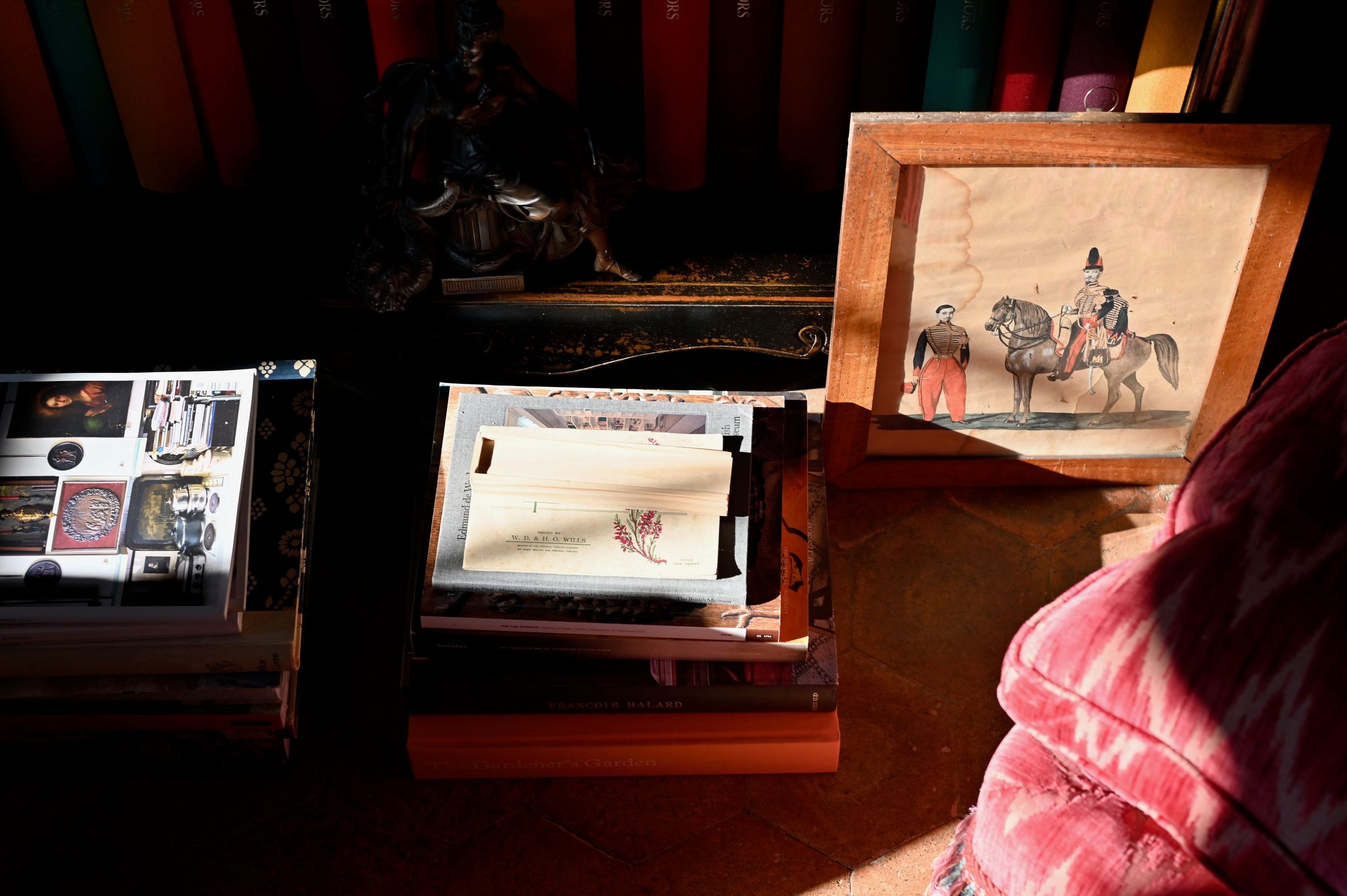 sun hitting a stack of antique paintings and drawings against the wall