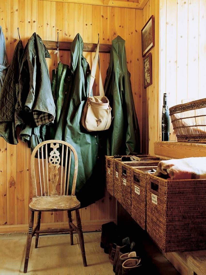 Wooden mudroom with coats, leather bag, and labeled baskets. Shoes on floor. Soft light through window highlights Jura's beauty.