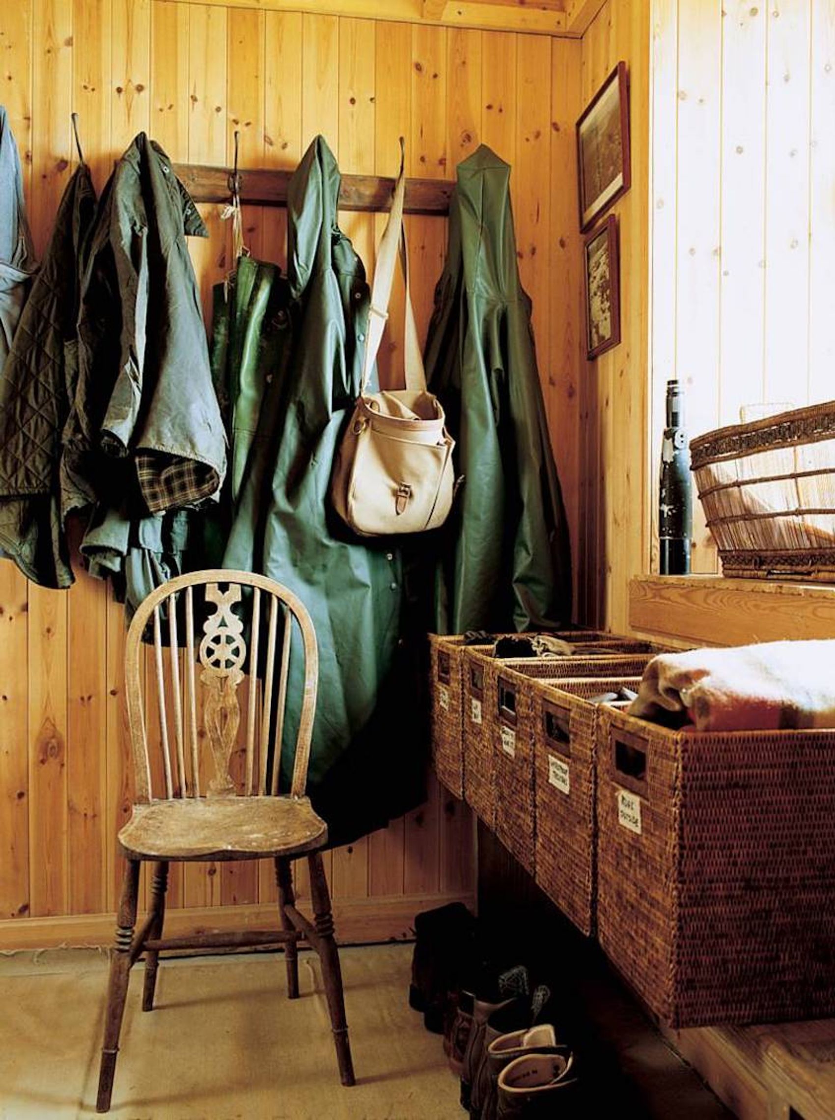 Wooden mudroom with coats, leather bag, and labeled baskets. Shoes on floor. Soft light through window highlights Jura's beauty.