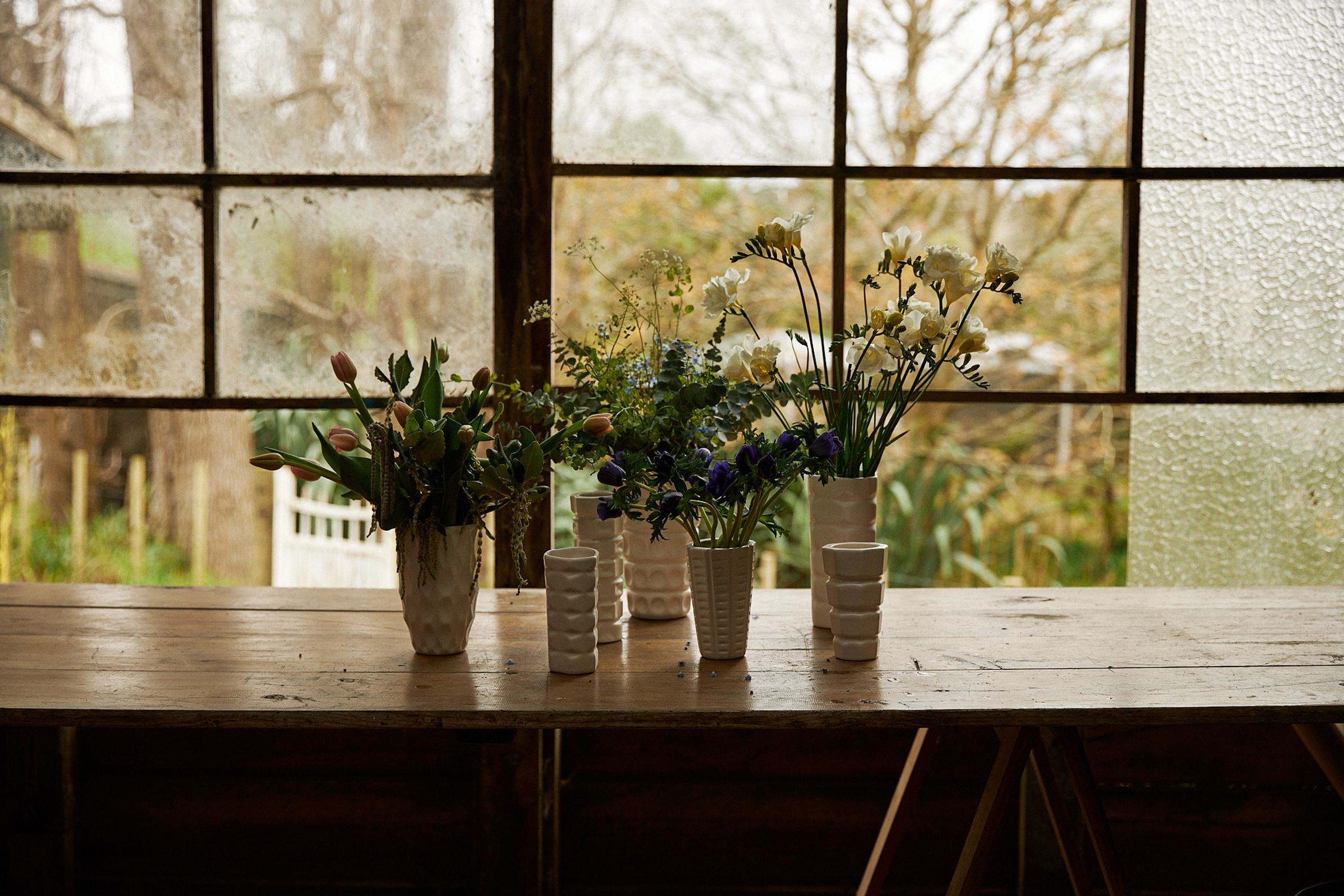 a line up of rachel carley ceramic vases in a flower barn against the windows