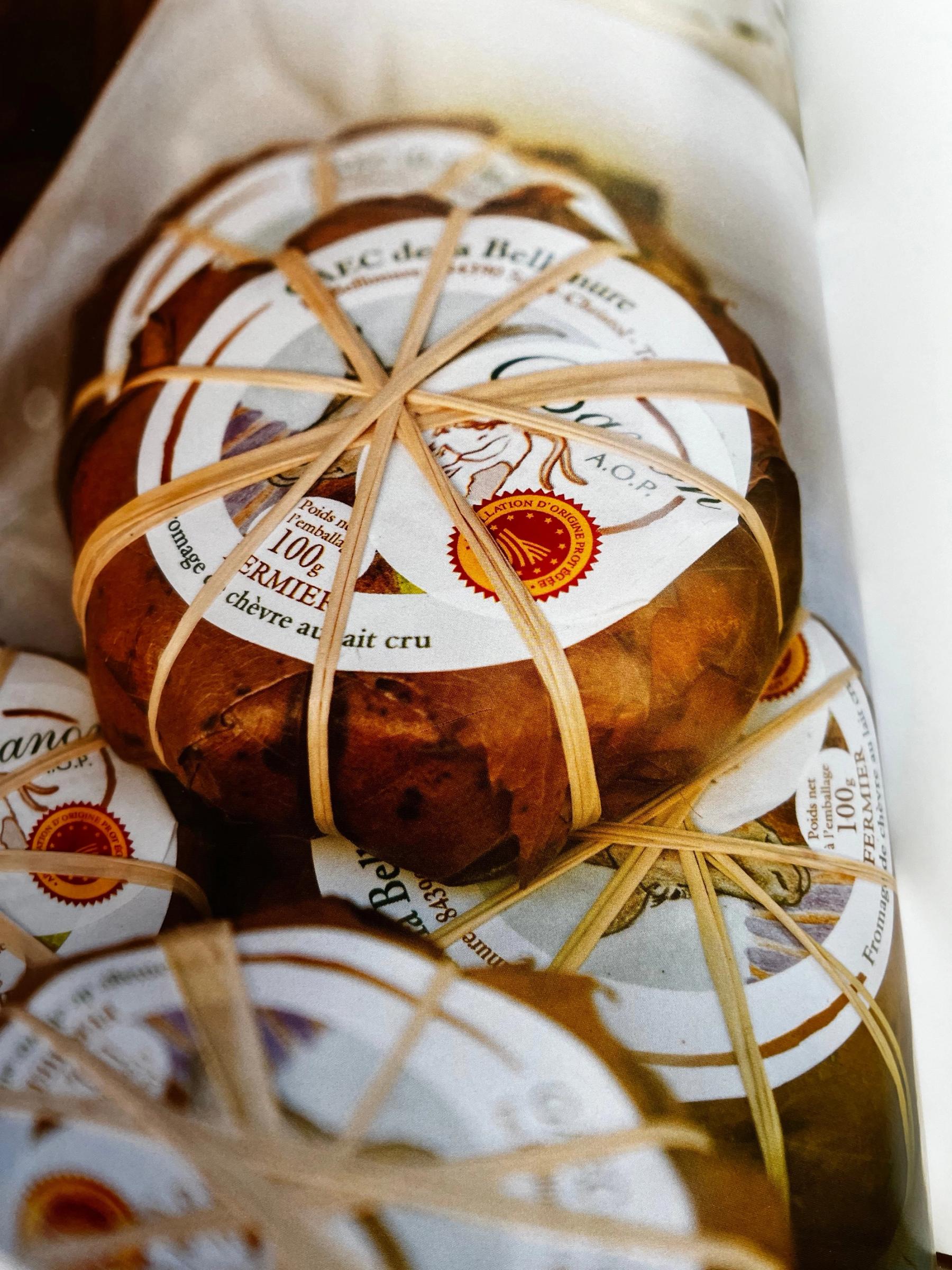 Stacked cheese packages wrapped in brown paper with rubber bands. White labels indicate goat's milk cheese.