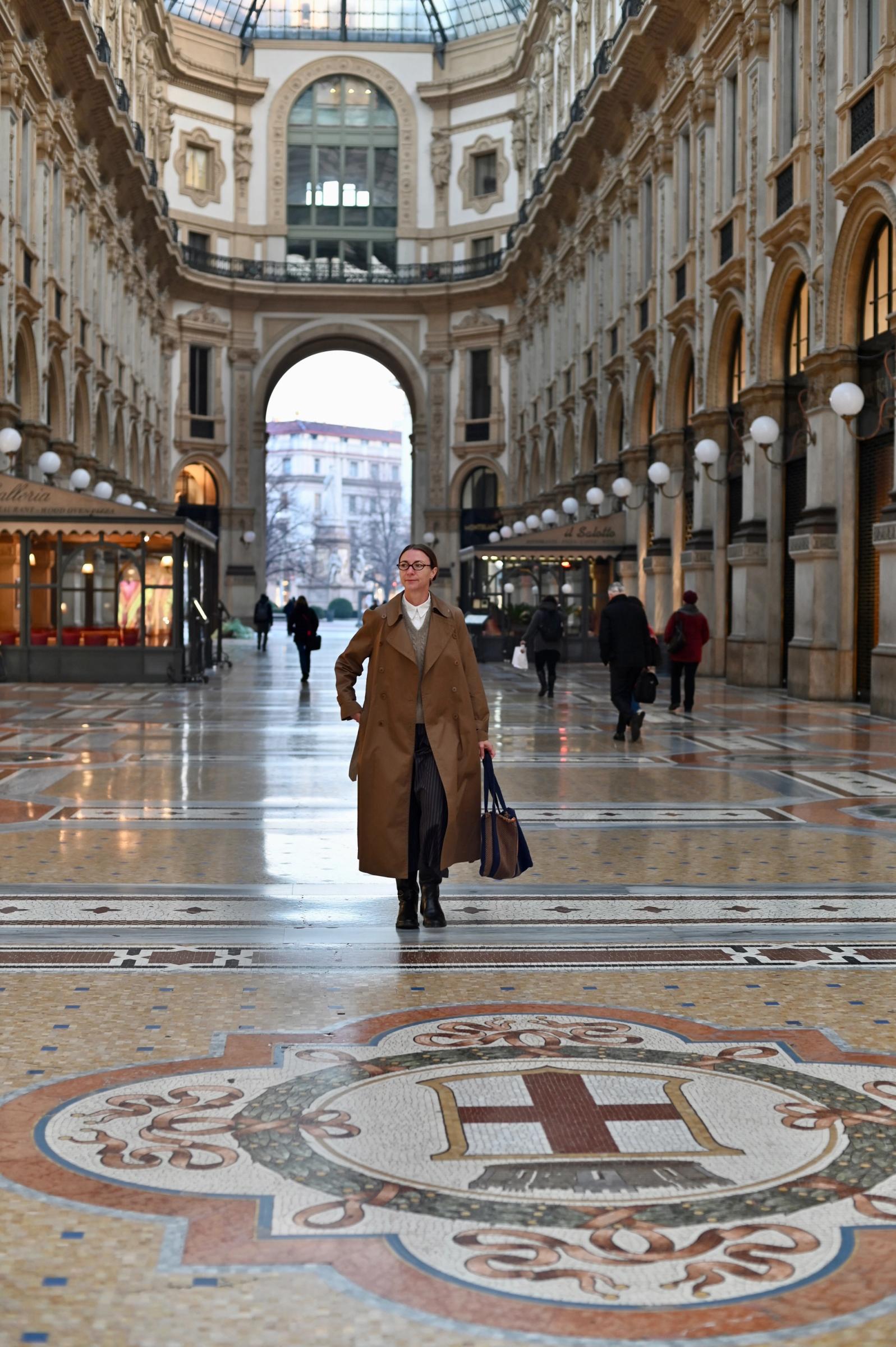women walking through halls over marble floors and trench coat swinging open