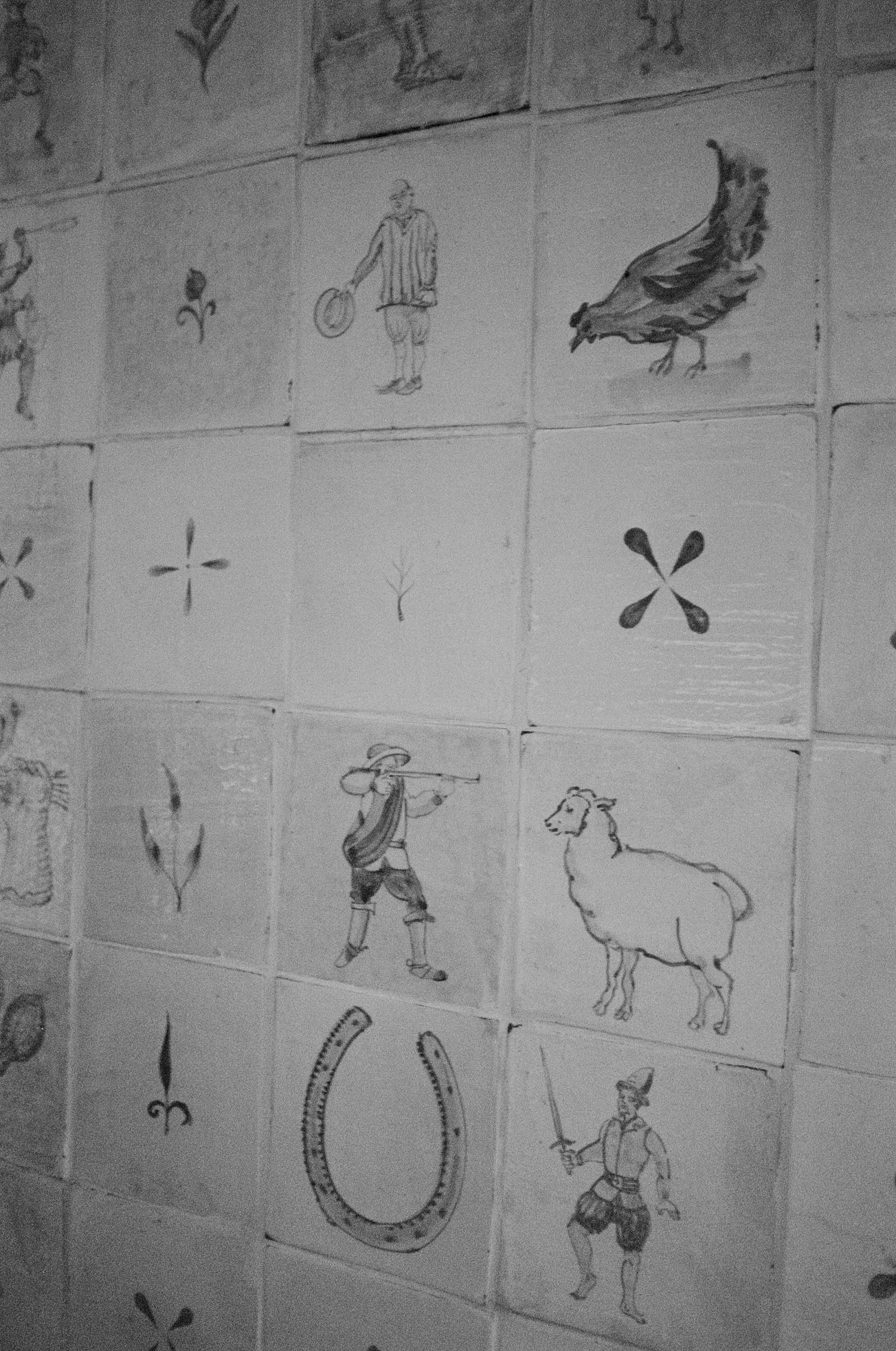 painted tiles with small drawings of horse shoes, chicken, sheep and jester