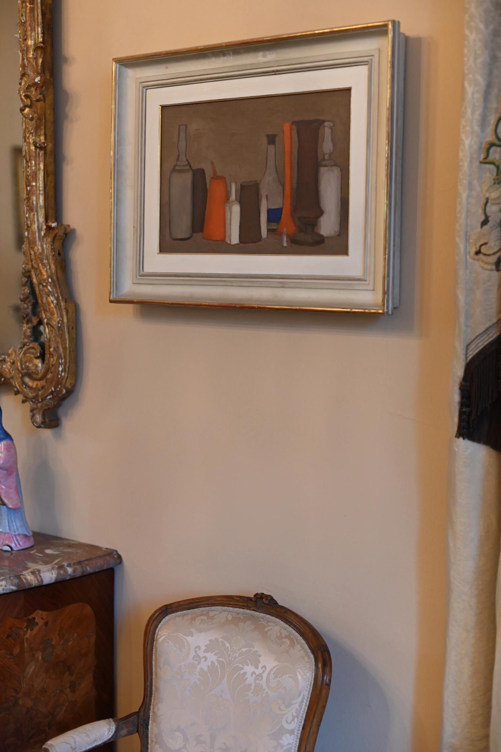 a real Morandi painting is hung above a chair and next to a mirror frame