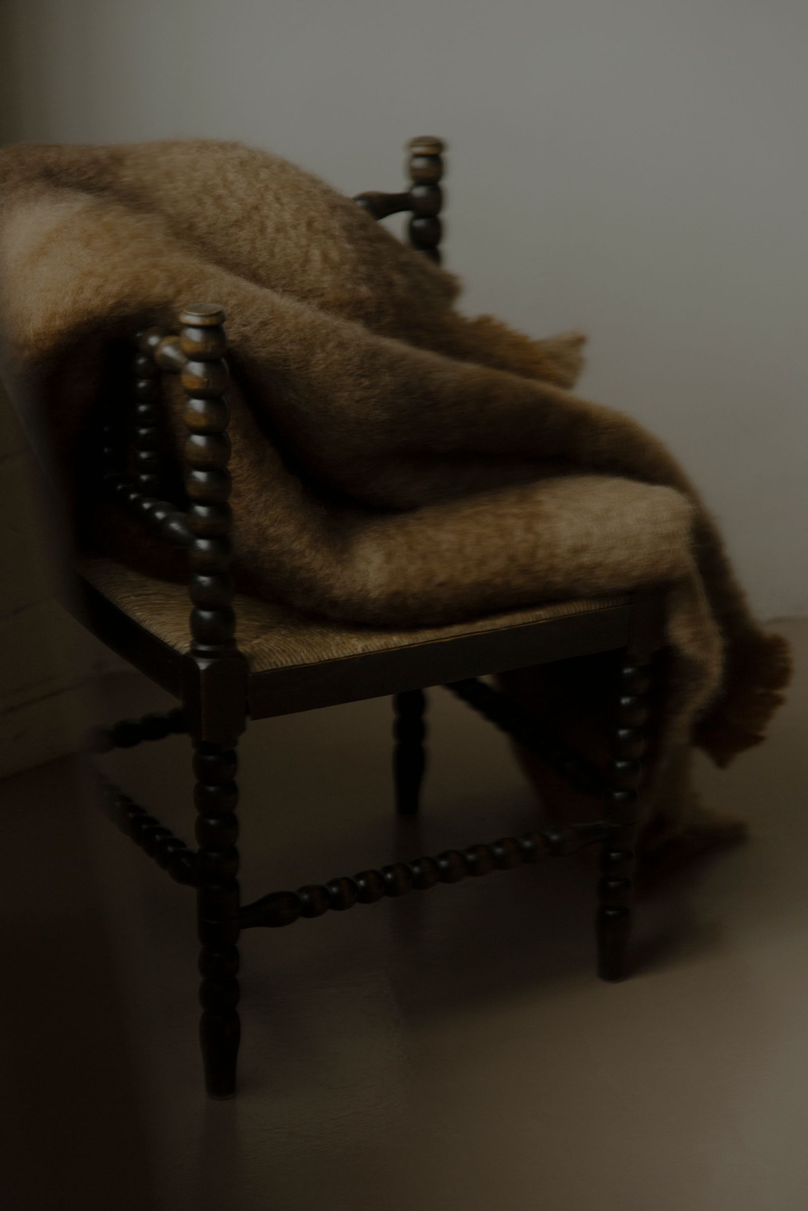 mohair blanket lays over the seat of a wooden bobble chair