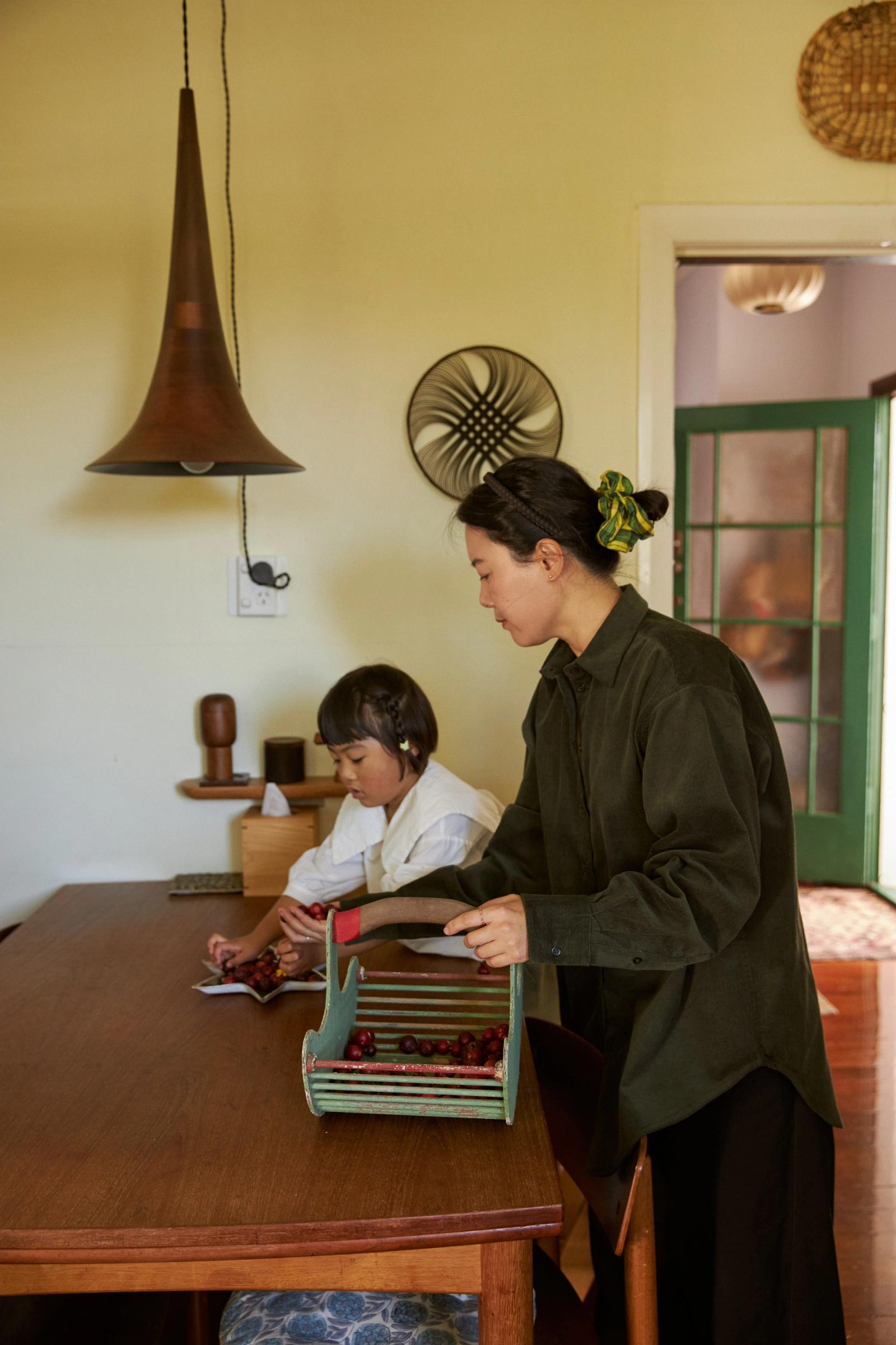 mother stand behind daughter at the dining table and under a wooden lamp