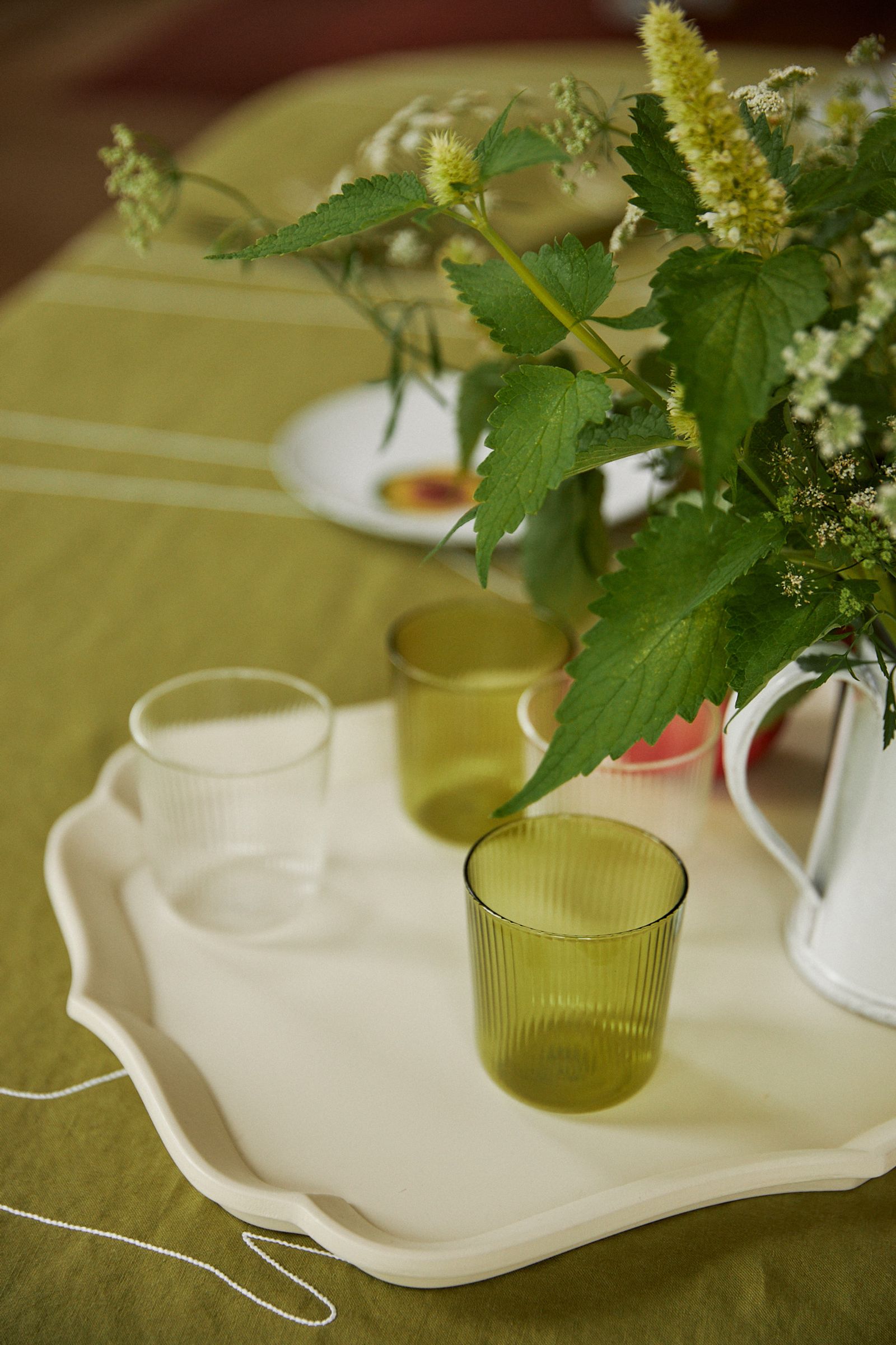 tray on green tablecloth with coloured glass and flowers