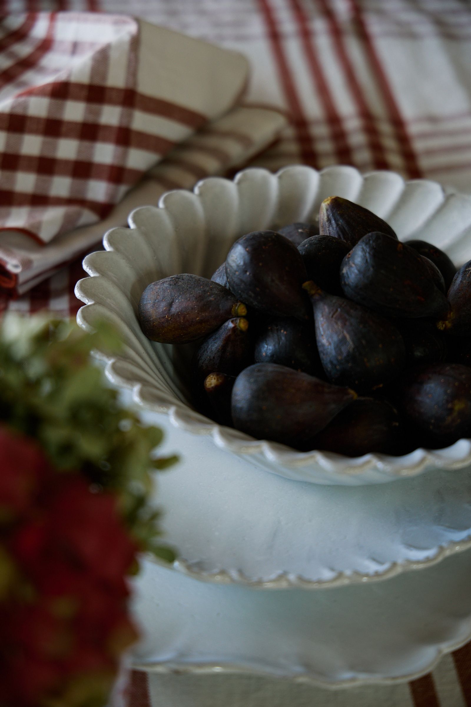 close up of fresh purple skinned figs in a stack of white plates