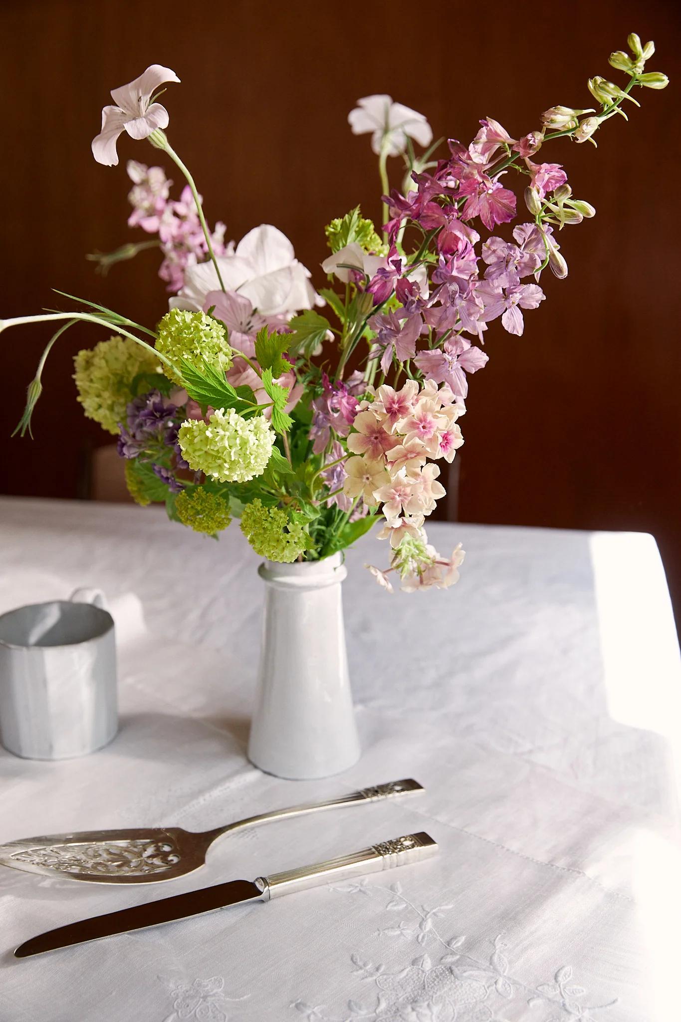 Wild spring blooms sit cheerfully in a white vase on the table