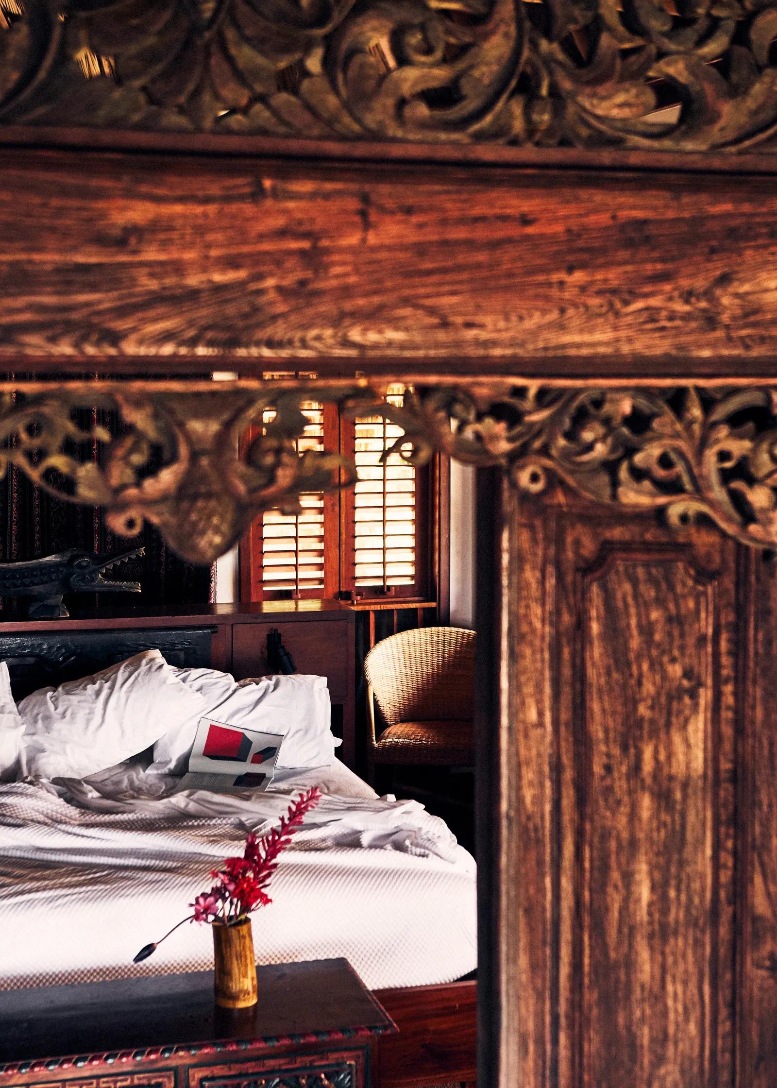 view through a wooden mirror of a hotel bed with a book left unread on the white sheets