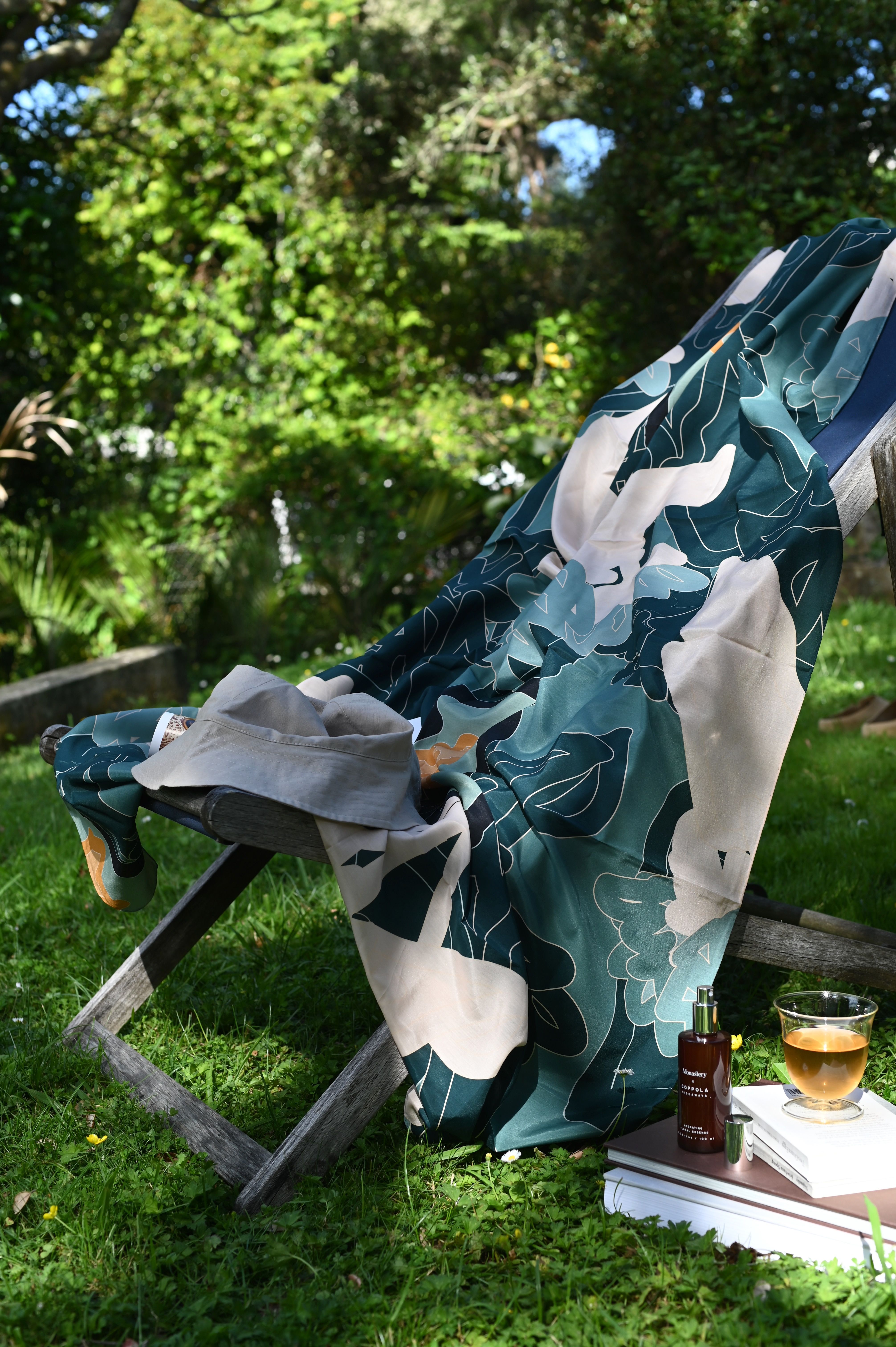 a floral sarong is thrown over a sling canvas deck chair in the garden