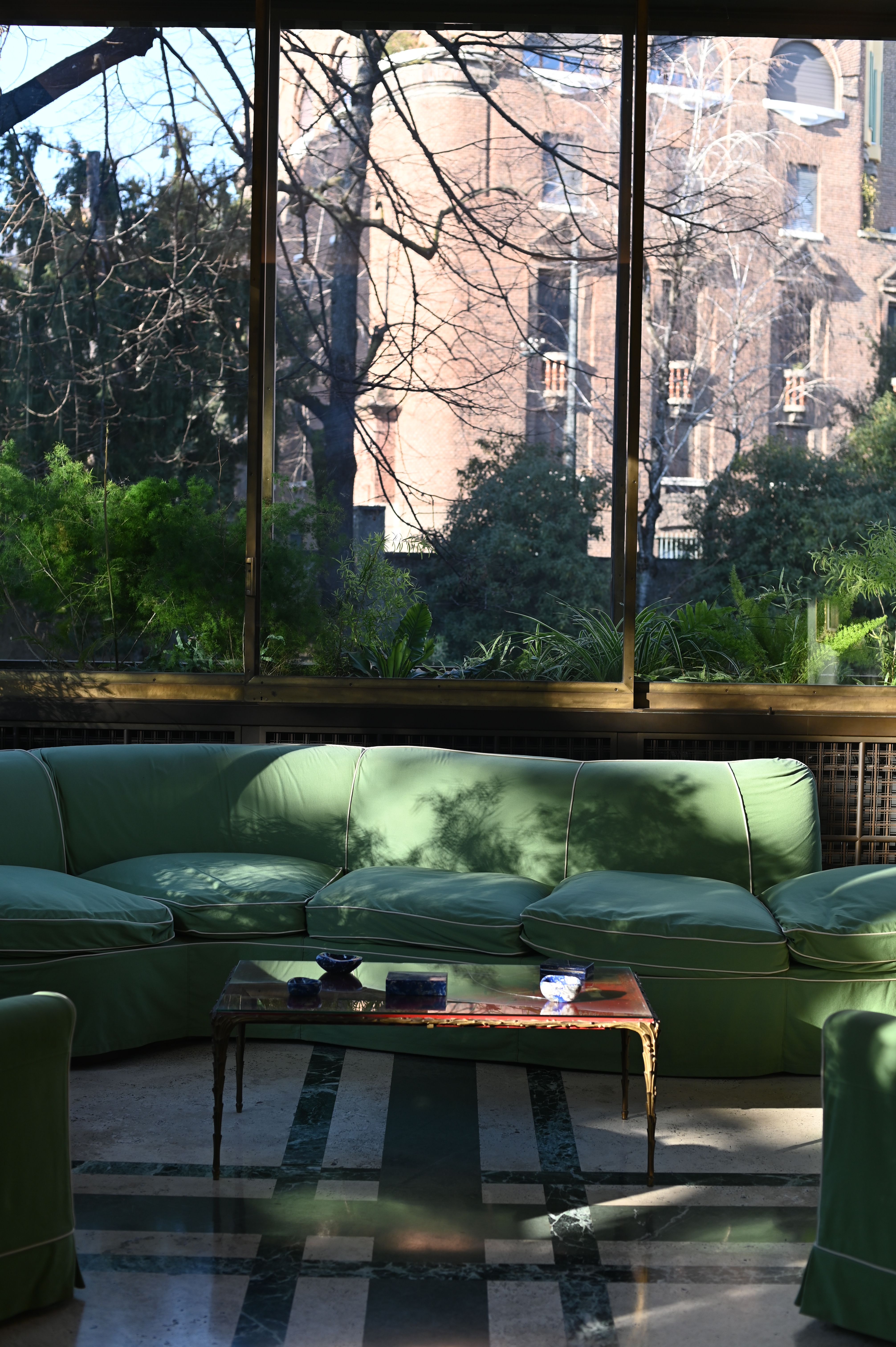 a green sofa is bathed in light in the conservatory room 