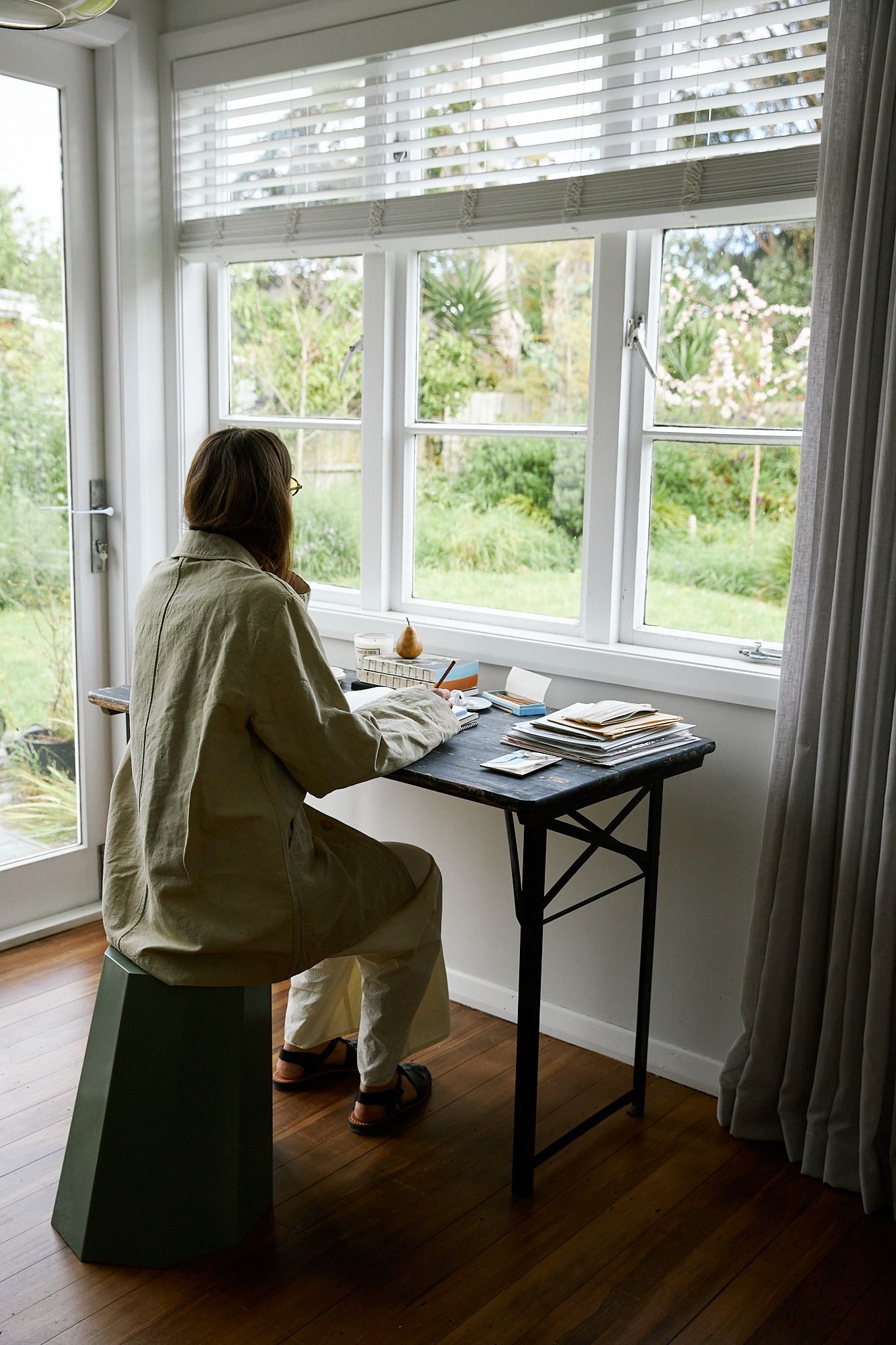 Woman sitting at desk looking out the window into the garden