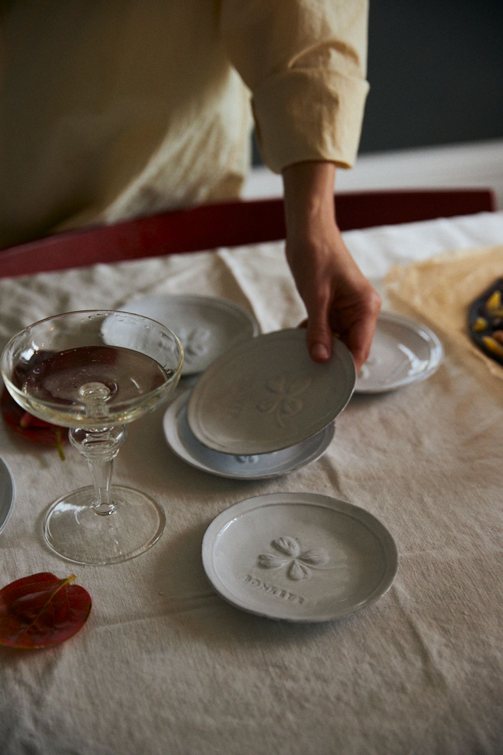 woman sets table with champagne glasses and small saucers