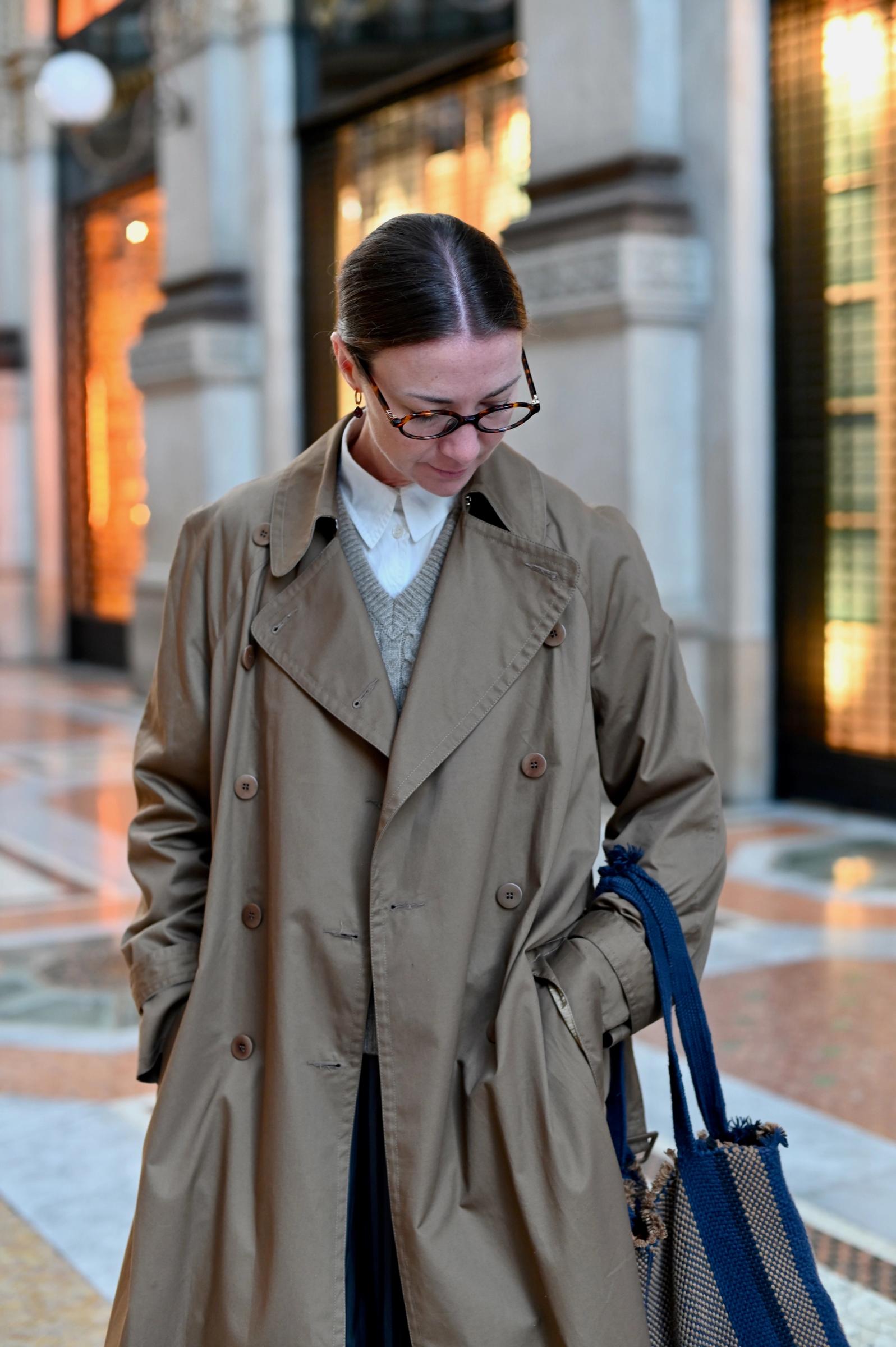 close up of trench coat featuring buttons and hand in pockets