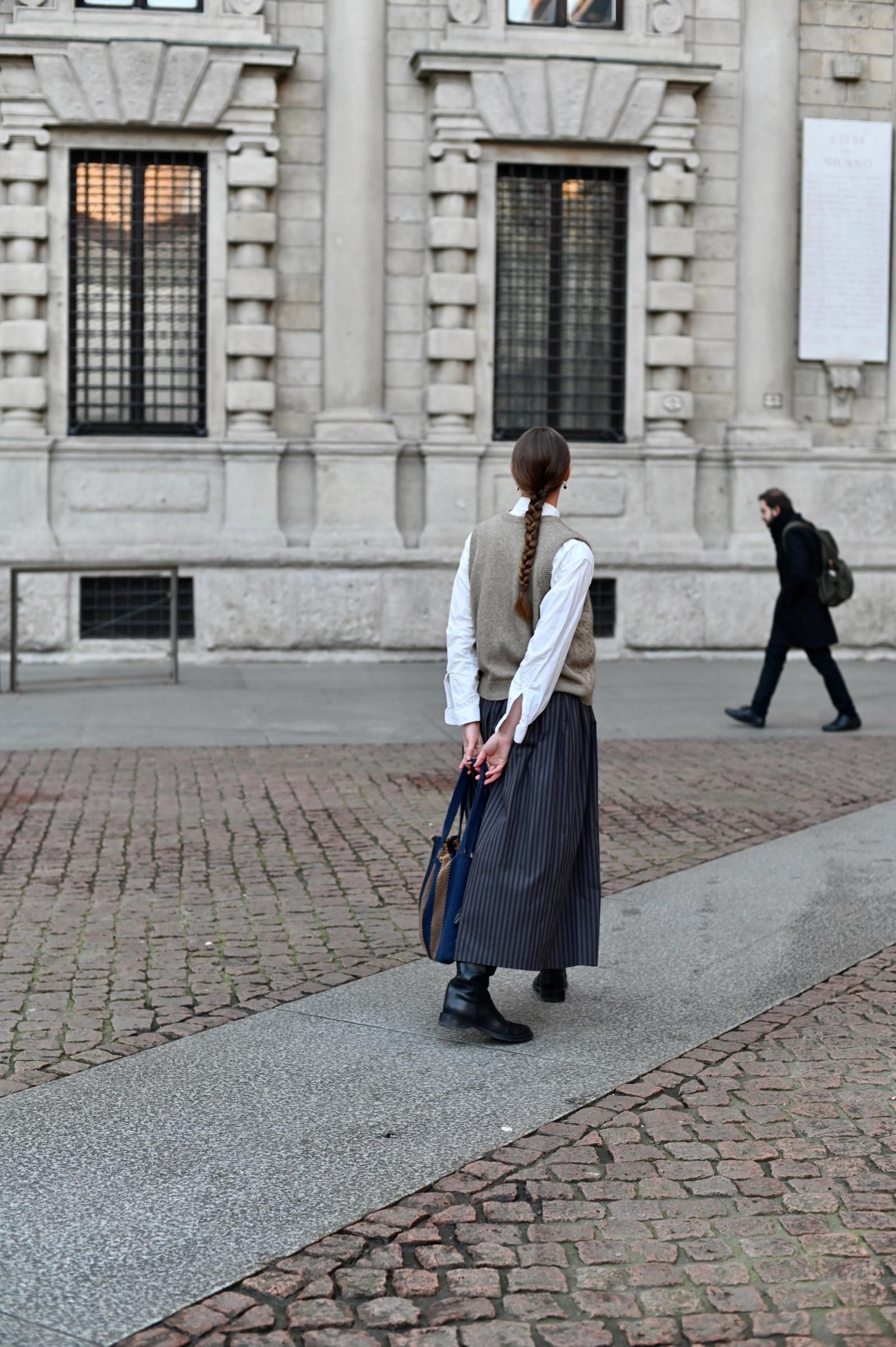 women wearing wool vest and stripe long skirt from behind