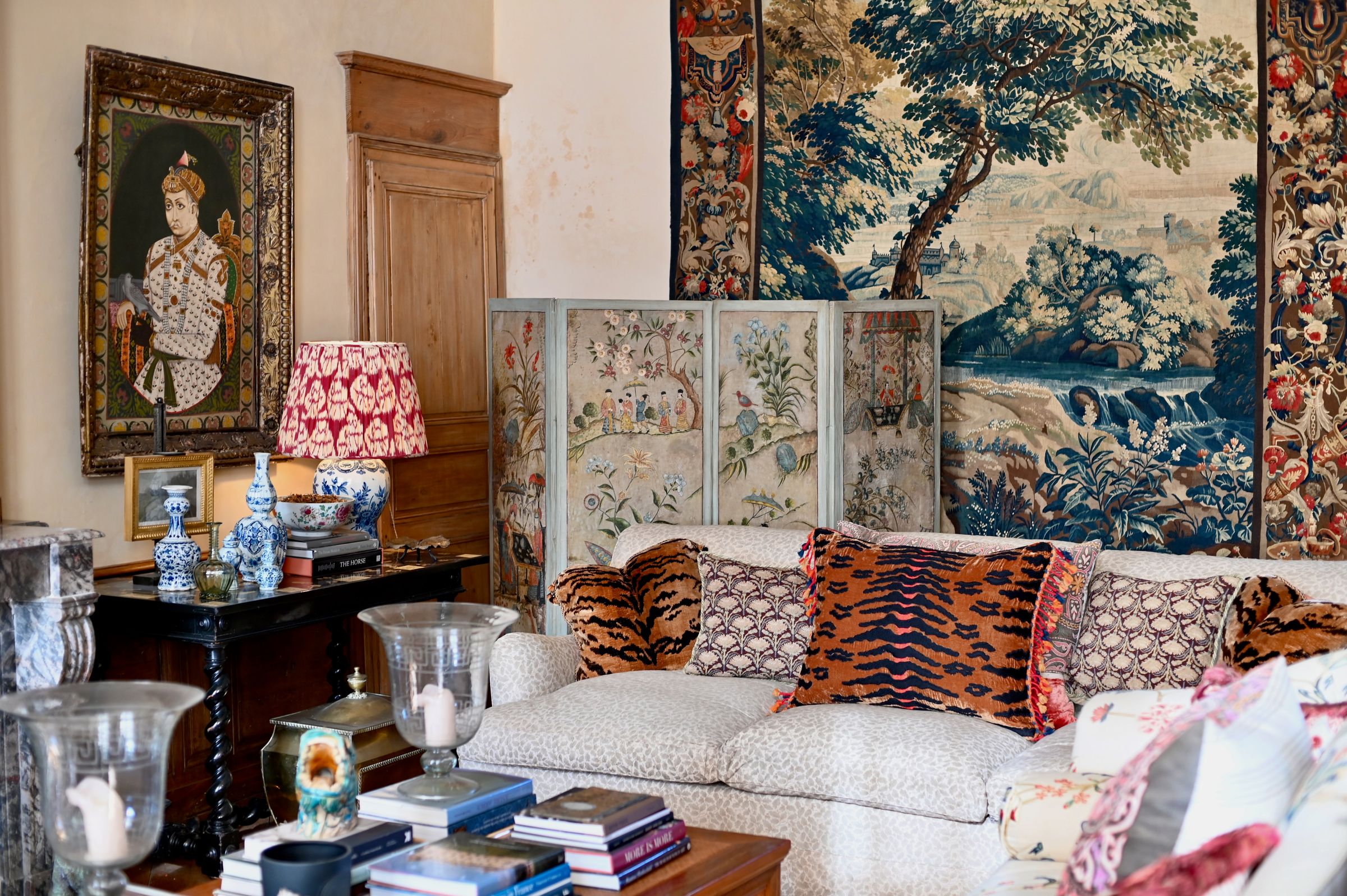 the sitting room with tapestries, fabric couches, lampshades and books
