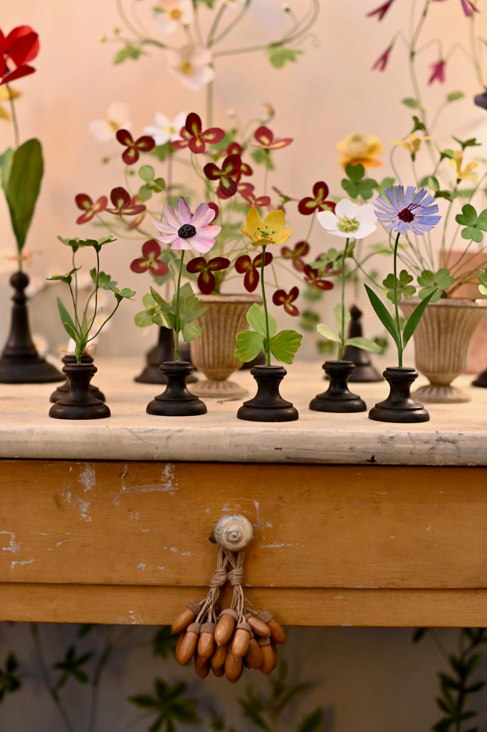 colourful flower sculptures are gathered on an old table top