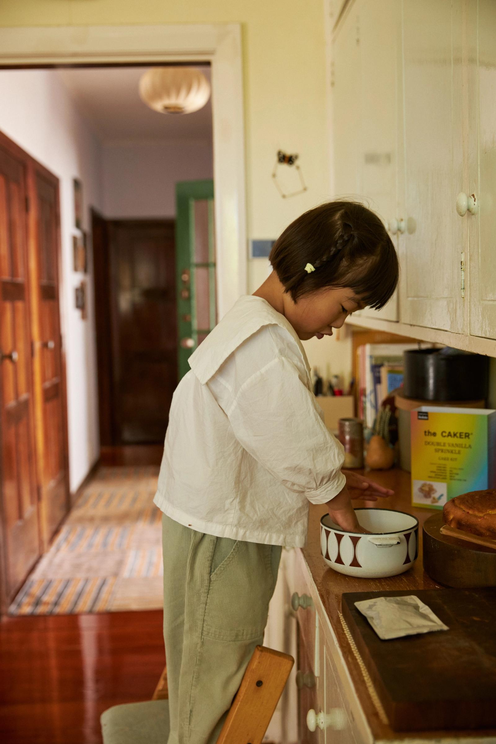 Eden wipes clean a bowl with a tea towel in the kitchen
