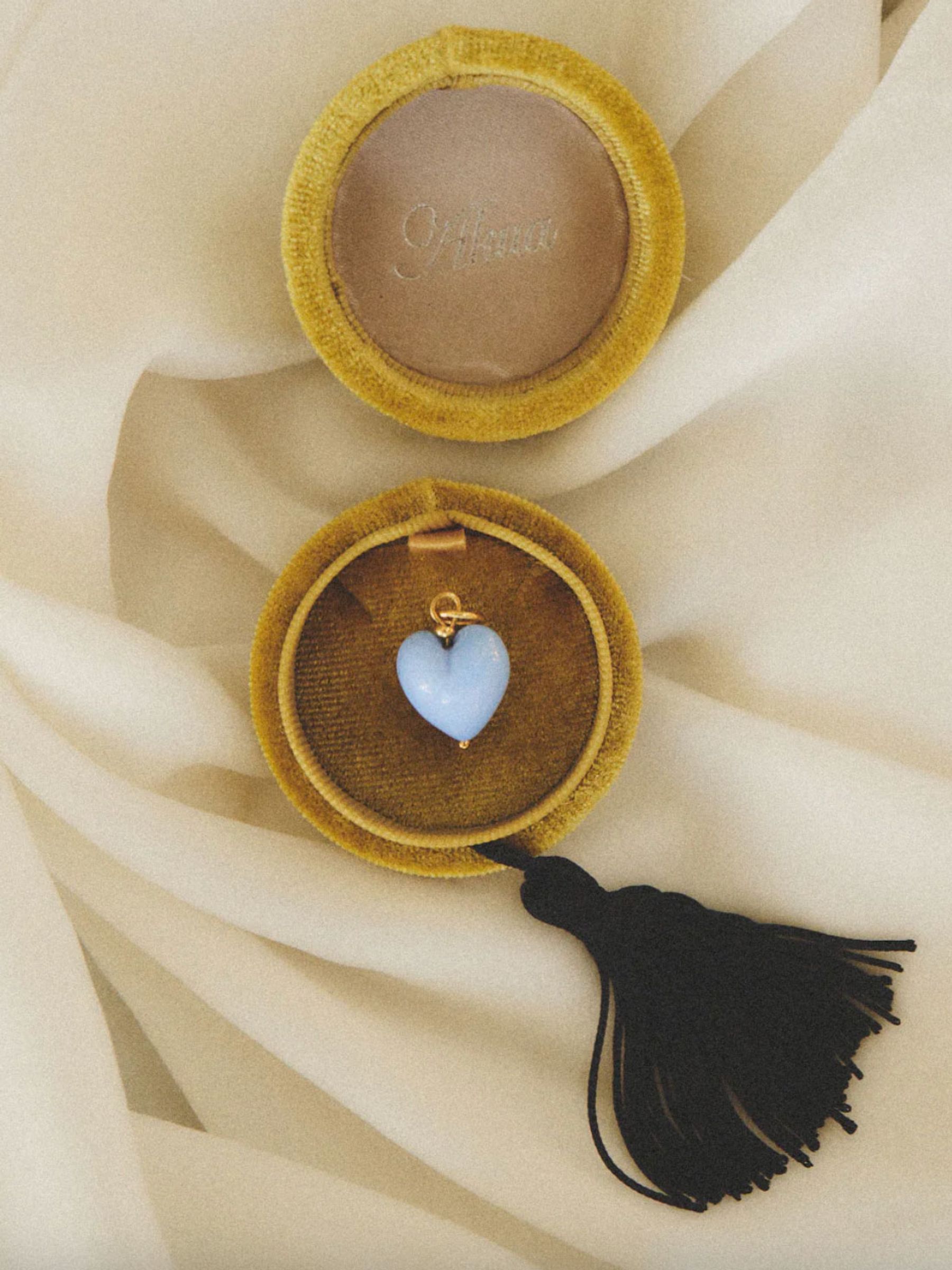 velvet circular box with a black tassel holds a blue stone pendant