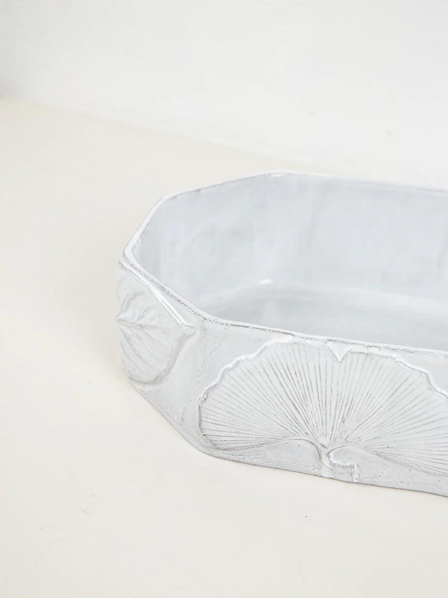 Light grey rectangular ceramic container with rounded corners. Embossed ginkgo leaf designs decorate sides, showcasing Astier de Villatte's handmade craftsmanship.