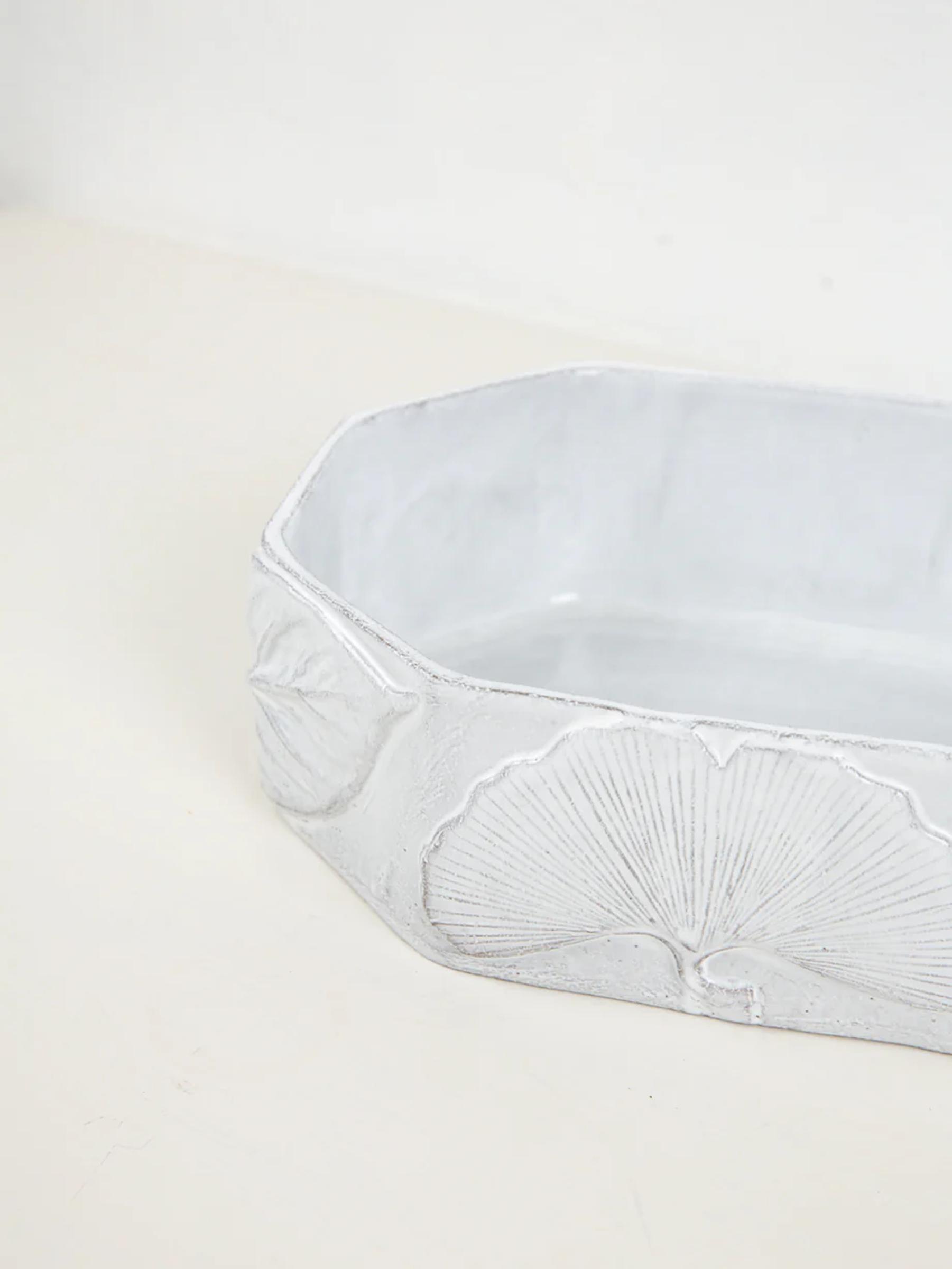 Light grey rectangular ceramic container with rounded corners. Embossed ginkgo leaf designs decorate sides, showcasing Astier de Villatte's handmade craftsmanship.