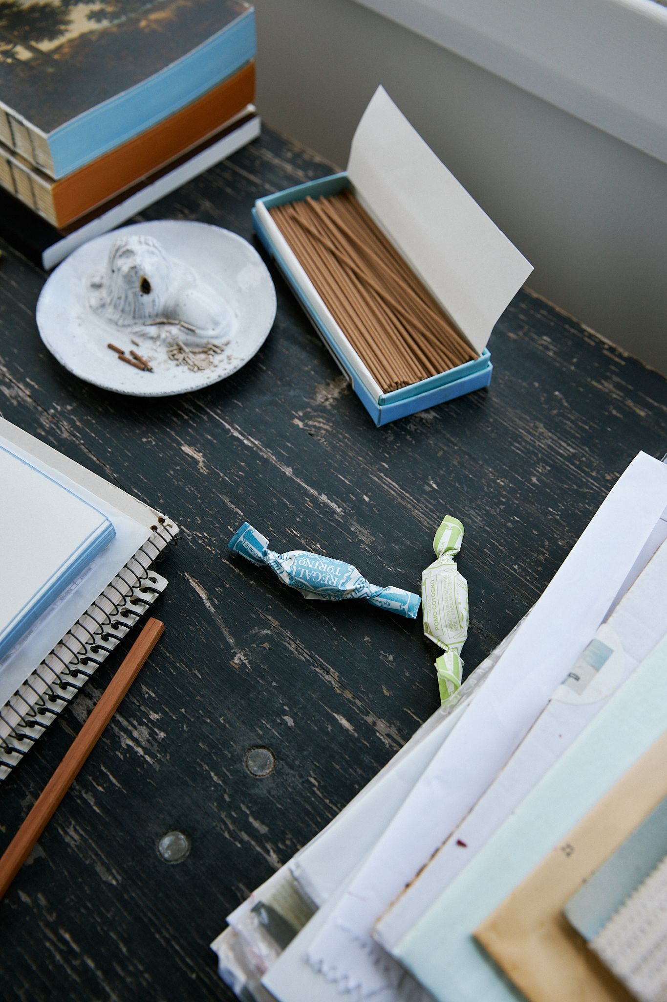 A snippet of desk featuring incense and sweet and books