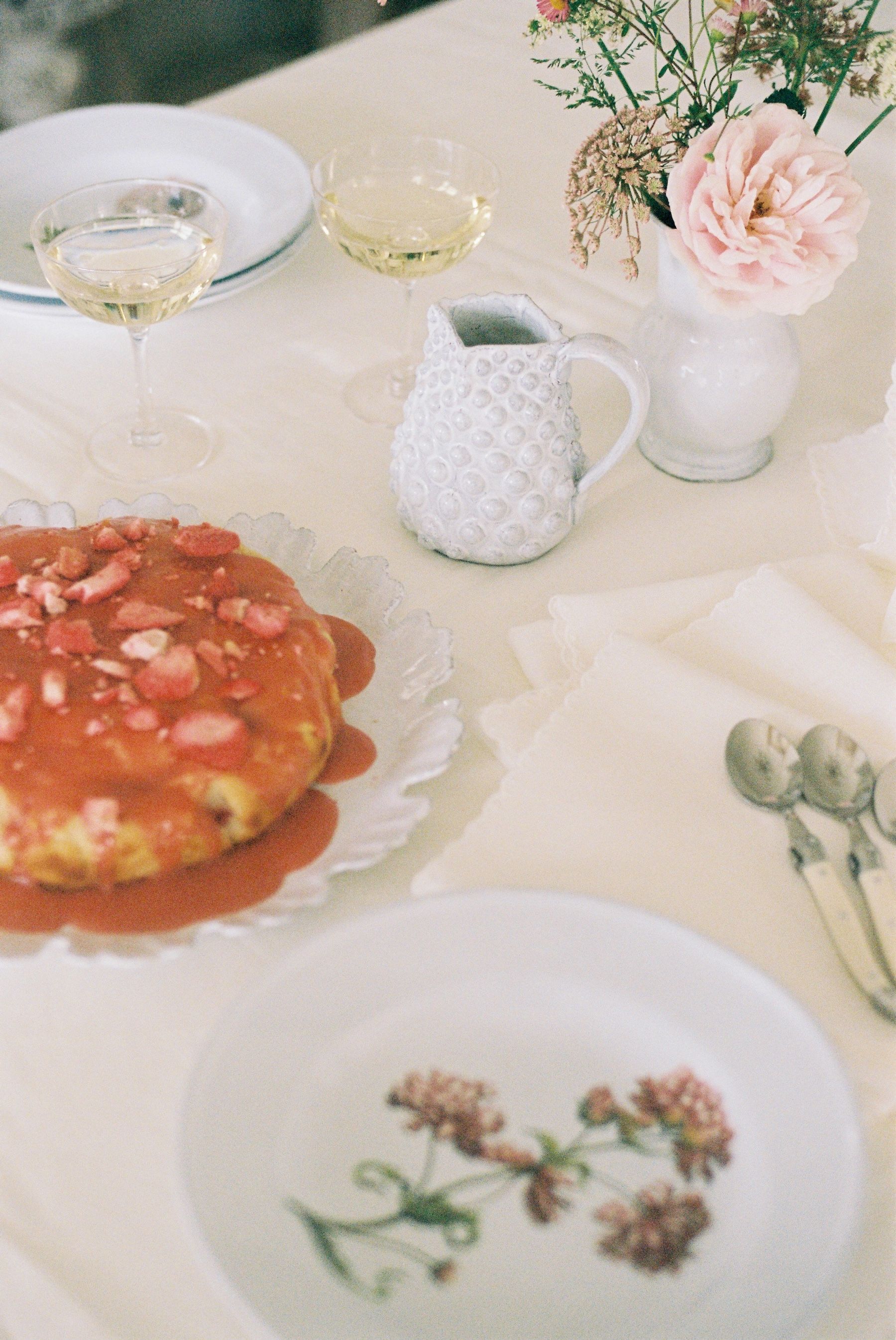 Table filled with plates, champagne and cake with pink icing 