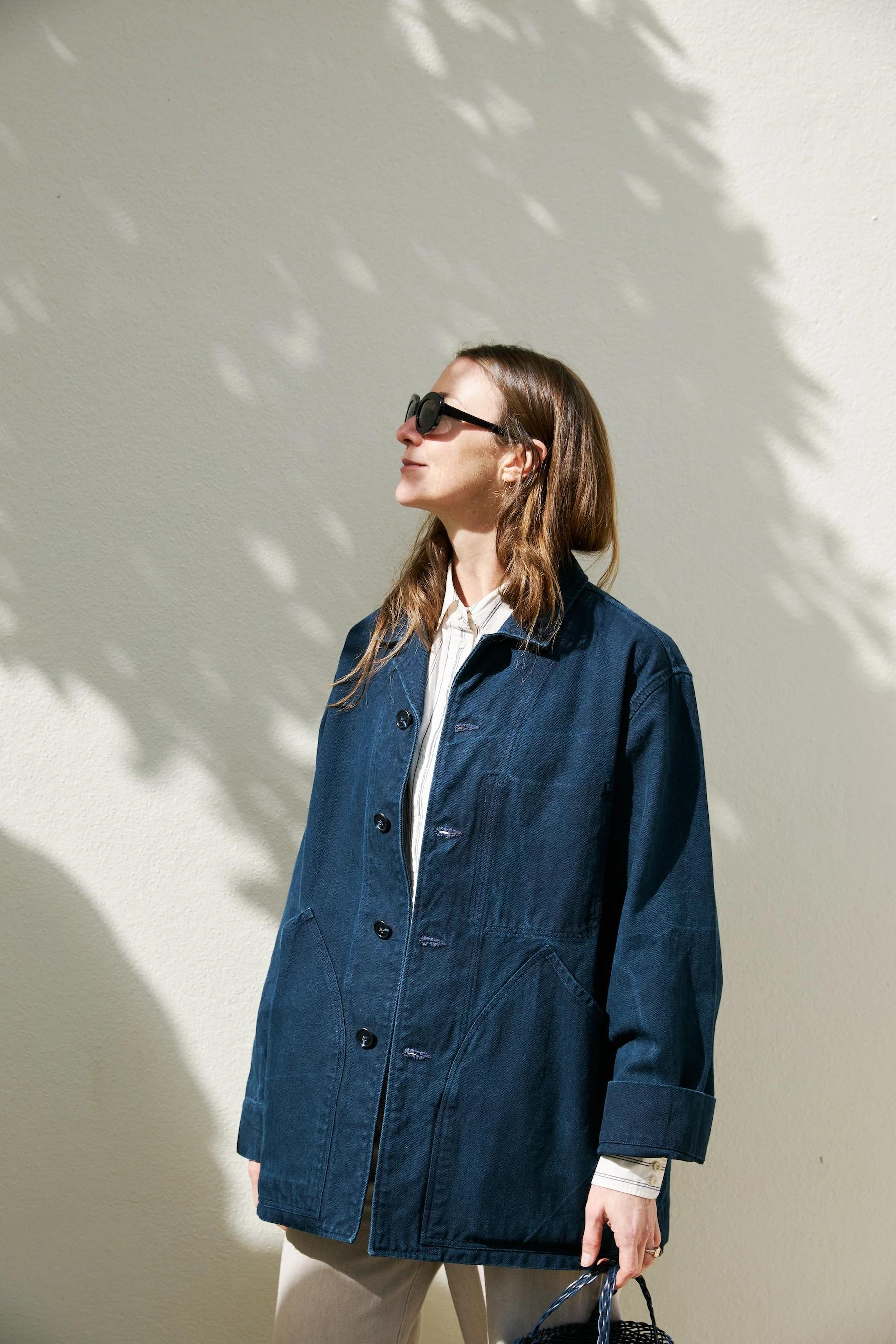 Indigo cotton jacket unbuttoned standing in the sun and worn over a collared shirt. 