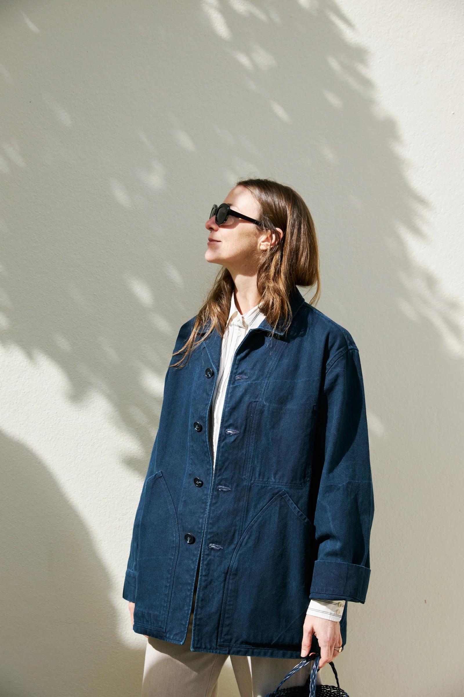 Indigo cotton jacket unbuttoned standing in the sun and worn over a collared shirt.