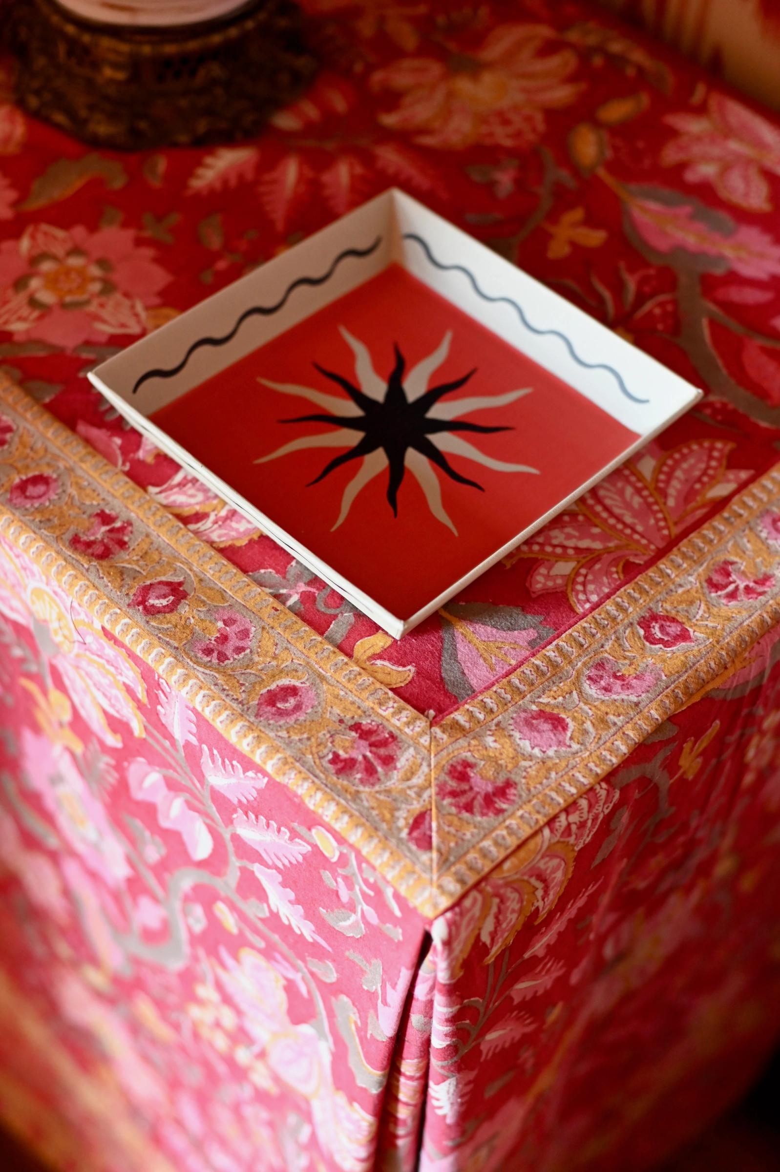 painted square dish sits on the corner of a fabric covered table