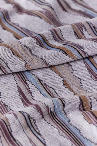 Close-up of fabric with wavy, abstract pattern in earthy tones. Soft, textured surface.