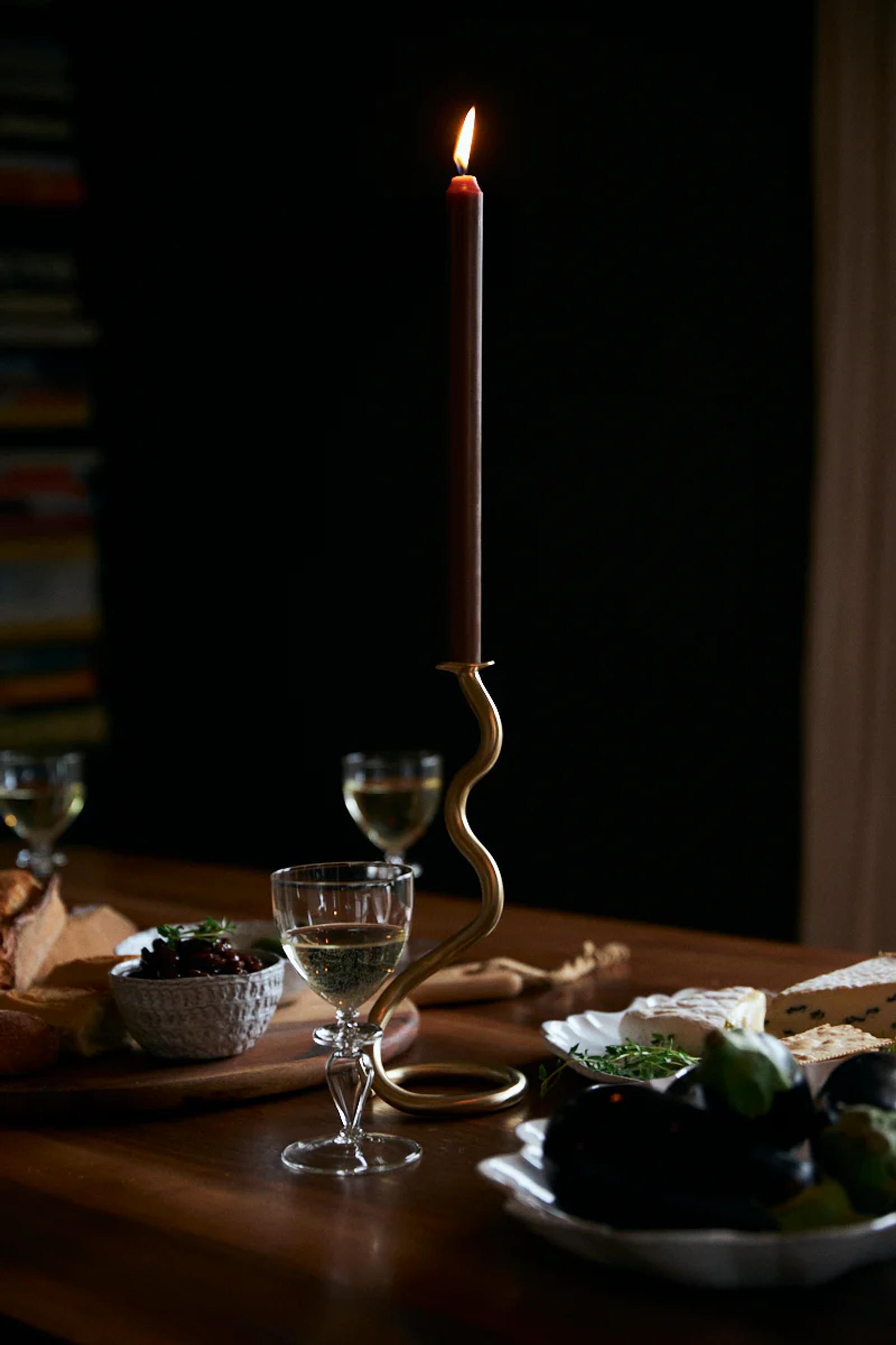 Candlelit table with wine, bread, fruit, and mostarda relish. Dark background creates cosy atmosphere.
