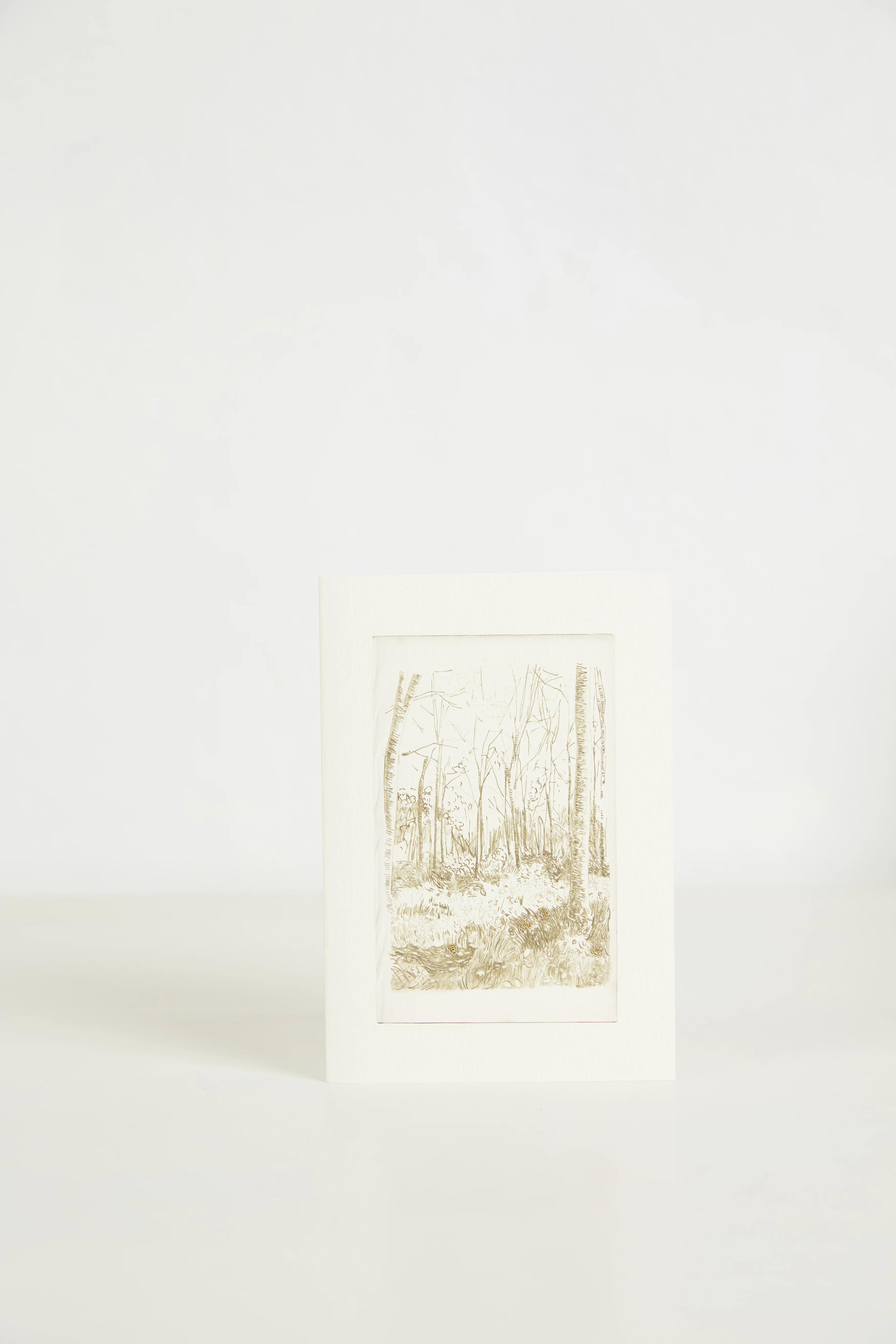 A greeting card with a sketched forest stands upright against a plain, white background. The trees drawn are bare or with light foliage.