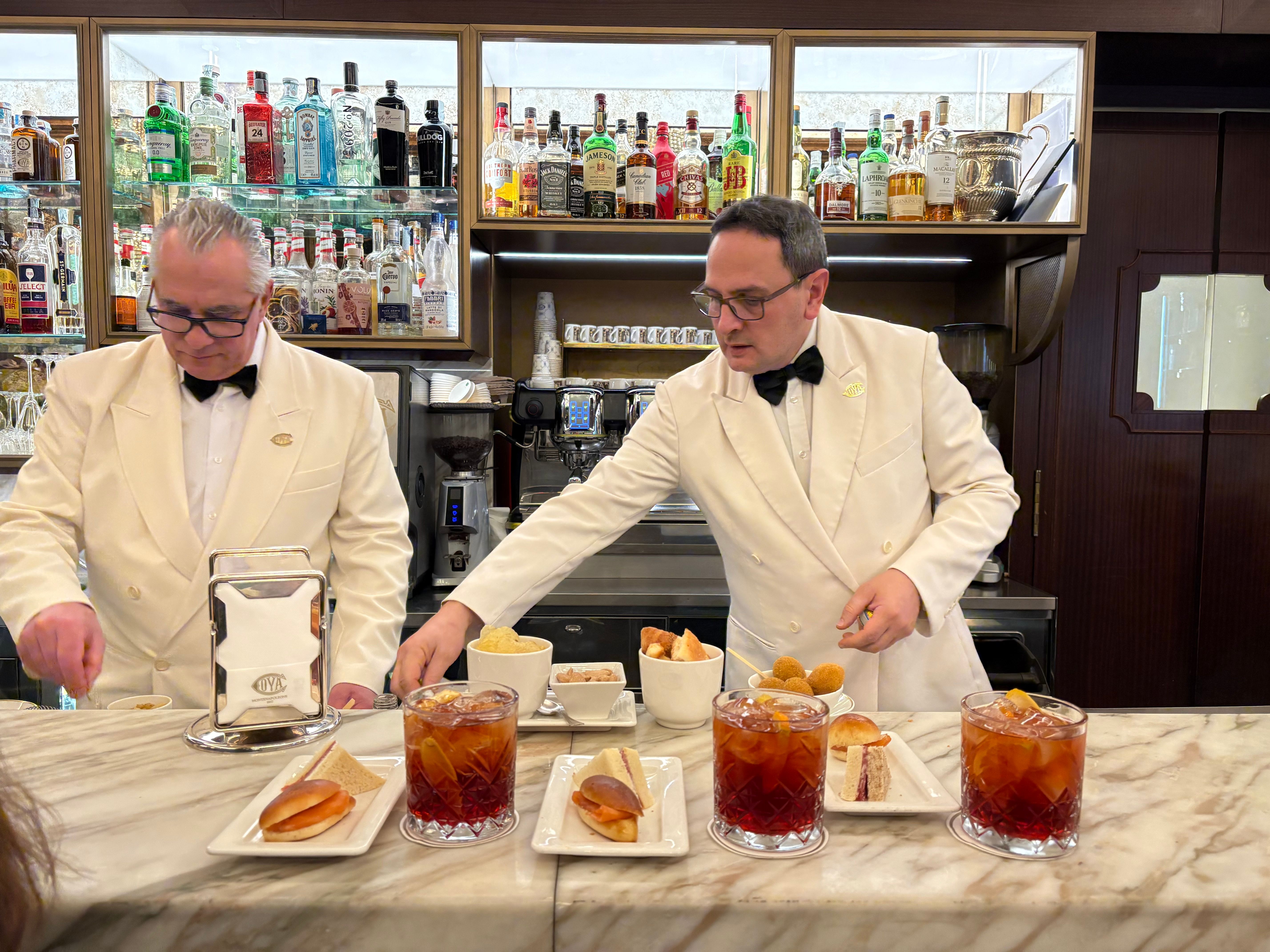 two waiters serve drinks and snacks in uniforms behind the bar 