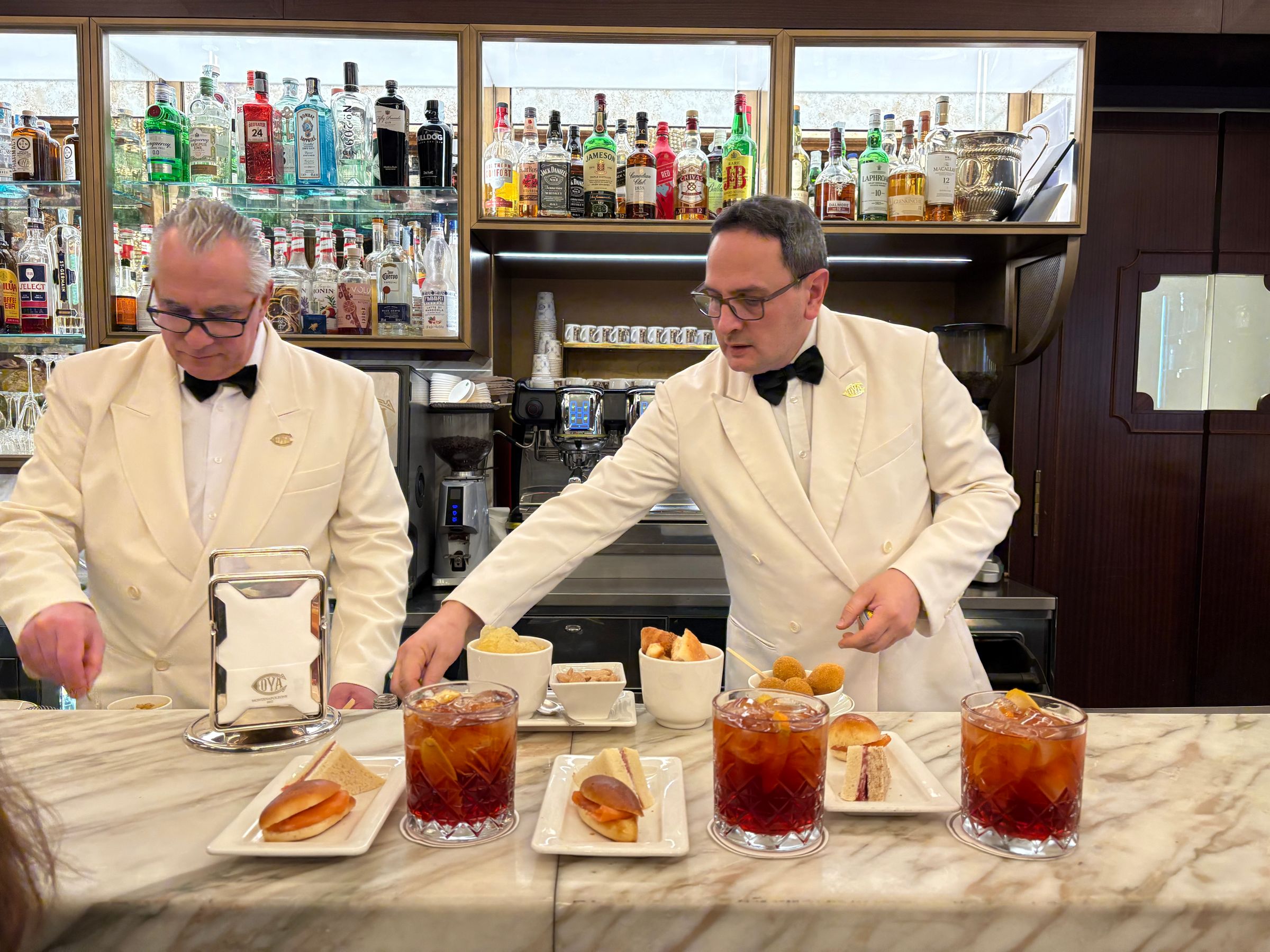 two waiters serve drinks and snacks in uniforms behind the bar